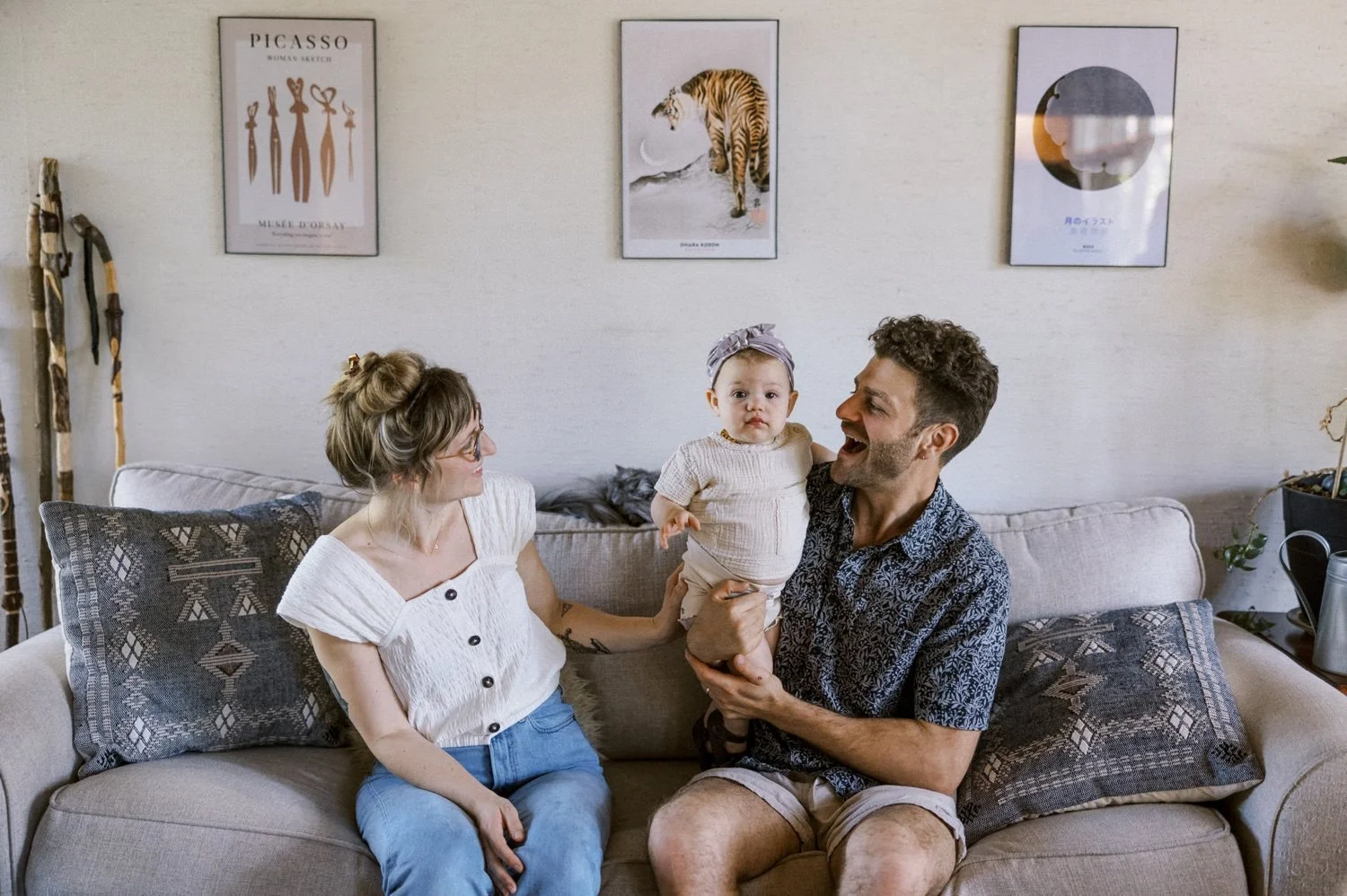 01_Portland Family Photographer-7028_woman in white shirt and blue jeans and man in blue floral shirt and khaki pants holding baby girl sit on couch.jpg