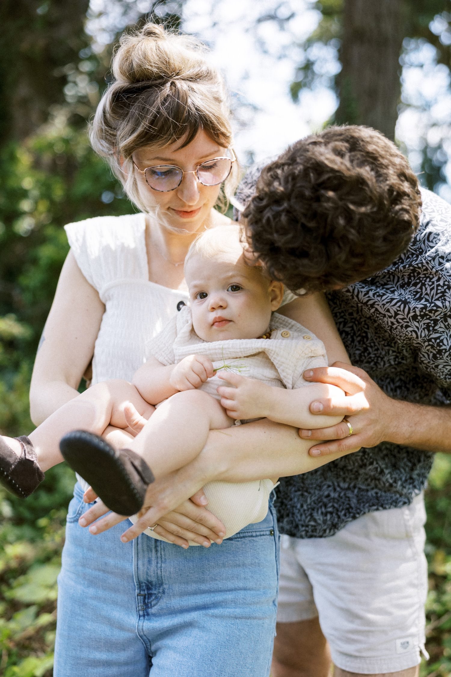 15_Portland Family Photographer-7440_dad gives baby daughter a kiss on temple while mom holds baby.jpg