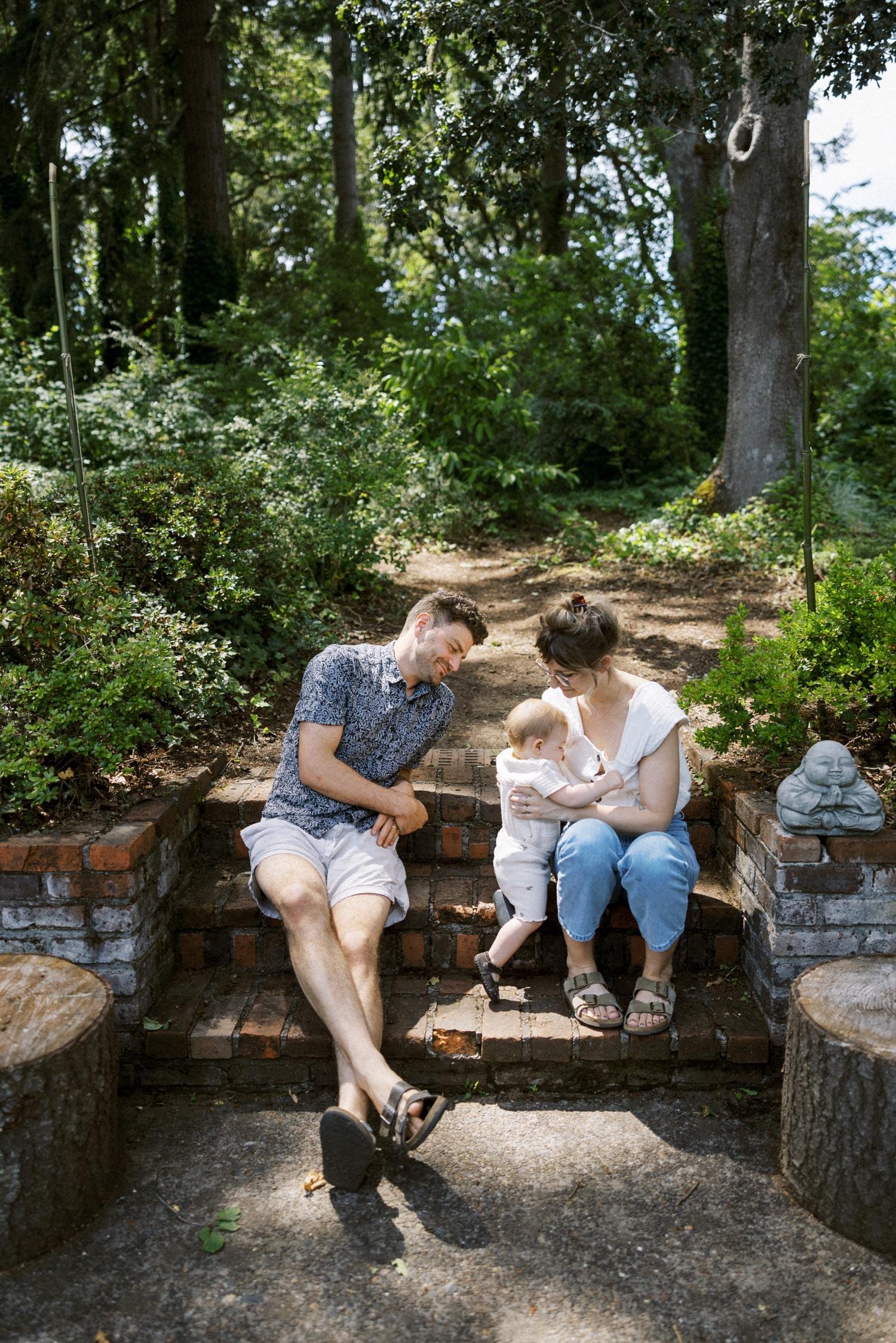 19_Portland Family Photographer-7684_mom and dad and baby daughter sit on brick steps together in back yard.jpg