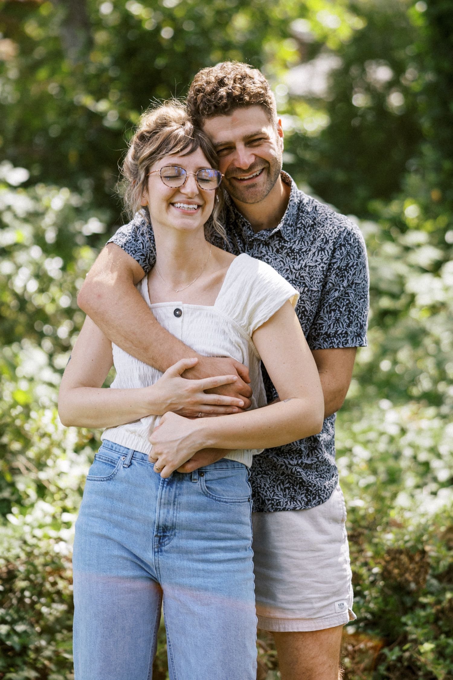 24_Portland Family Photographer-7949_man and woman hug each other while surrounded by greenery in backyard.jpg