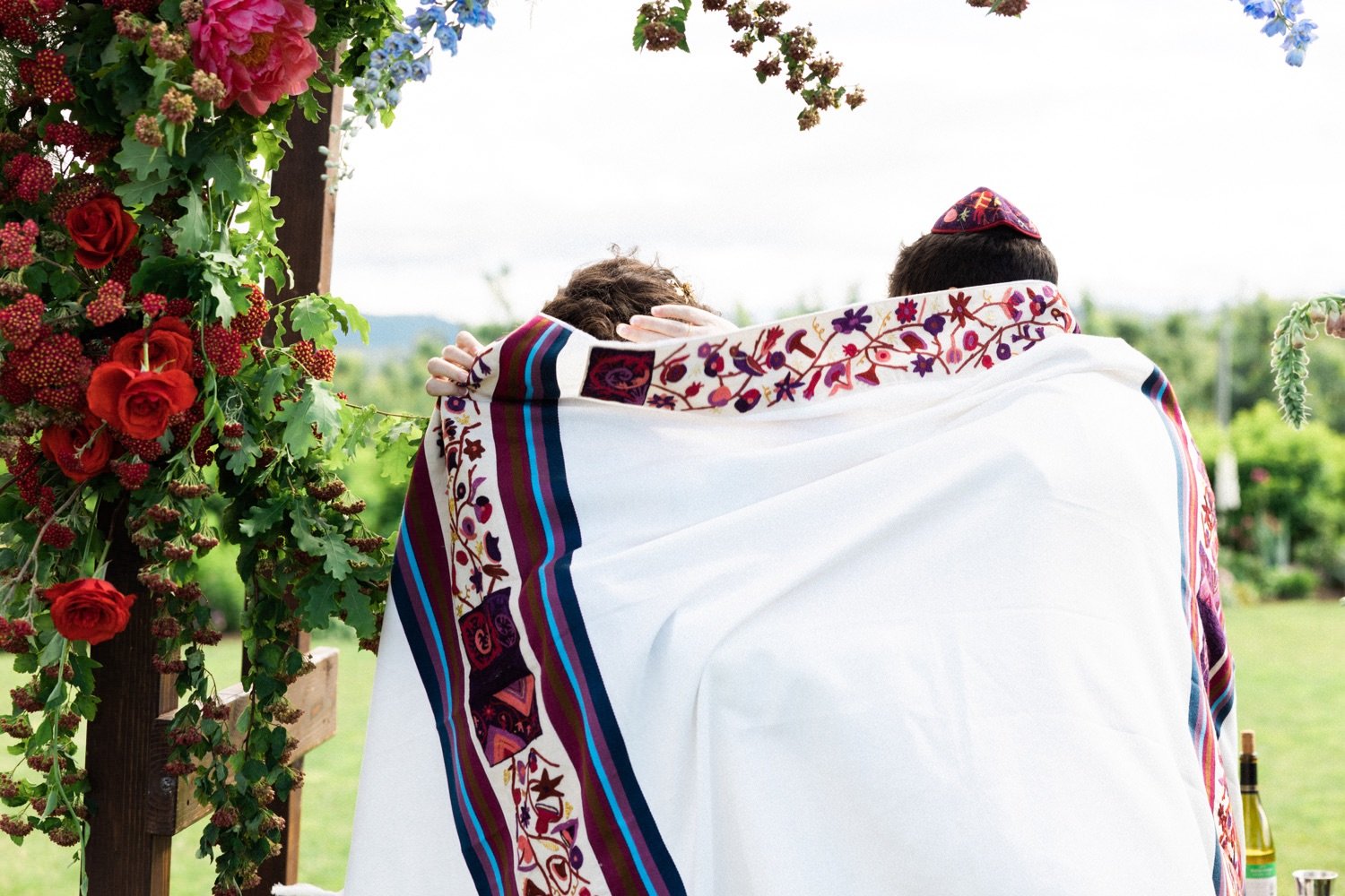 054_The Orchard Hood River Wedding96_bride and groom wrap in shawl during jewish wedding ceremony.jpg
