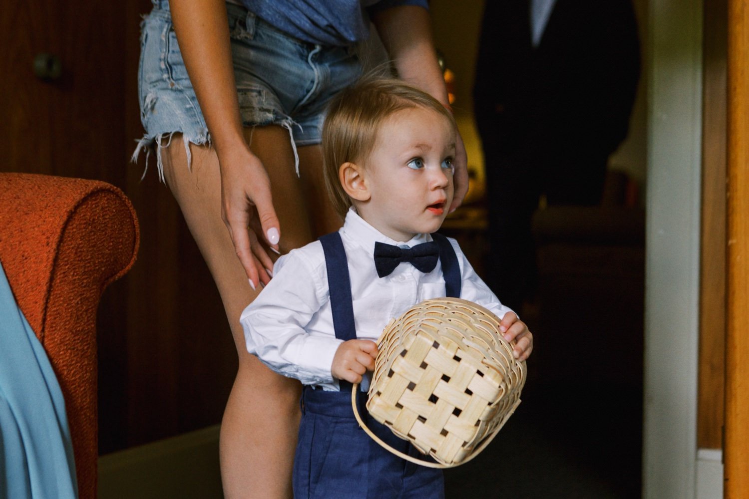 toddler in suspenders and bowtie carries wicker basket 