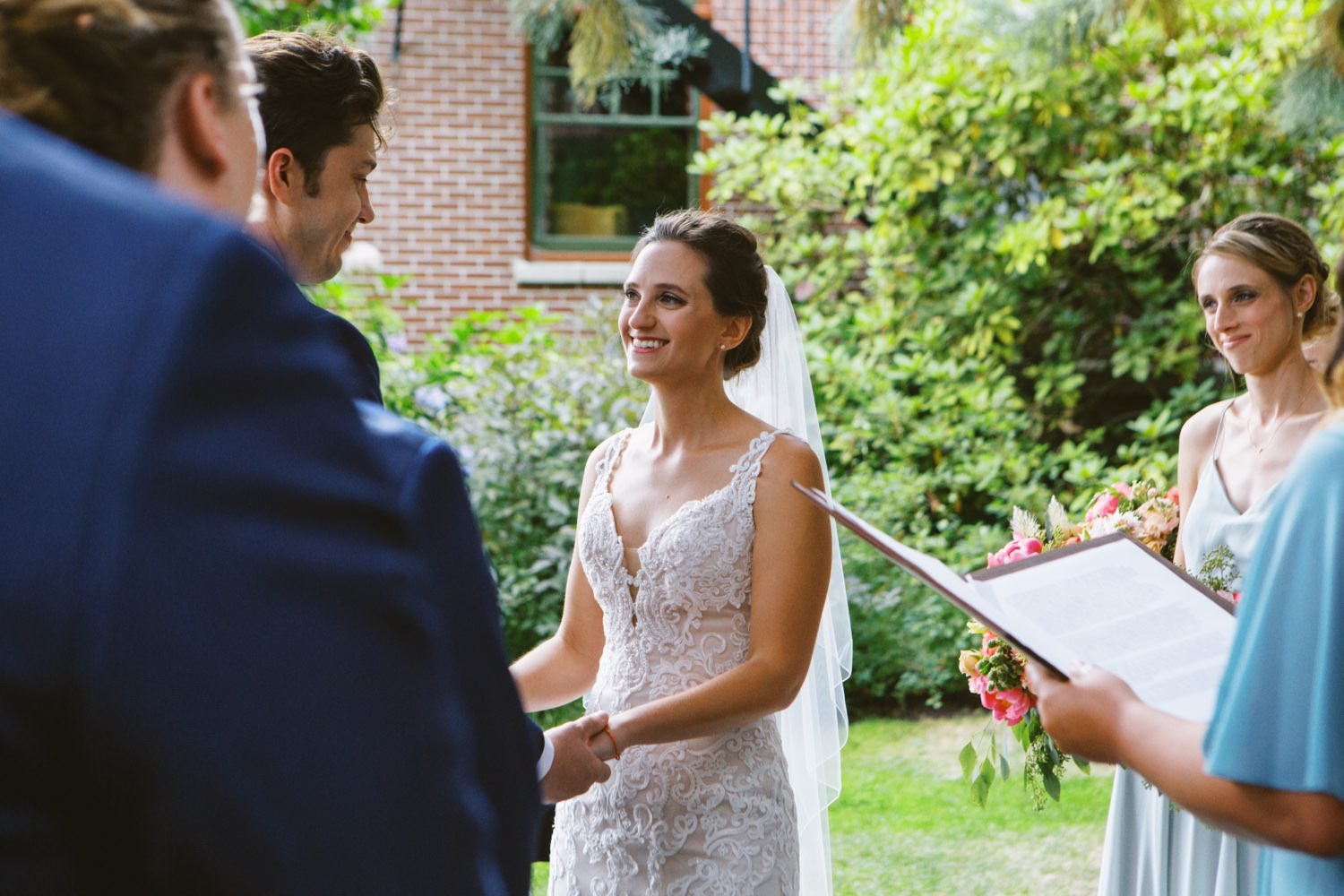  bride in white dress smiles at groom in blue suit 