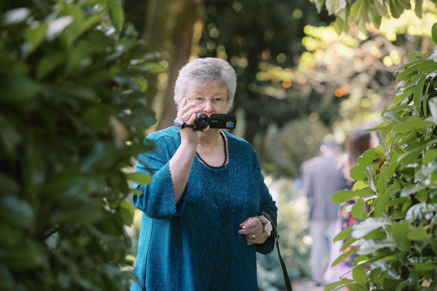  woman in teal outfit holds handheld video camera 