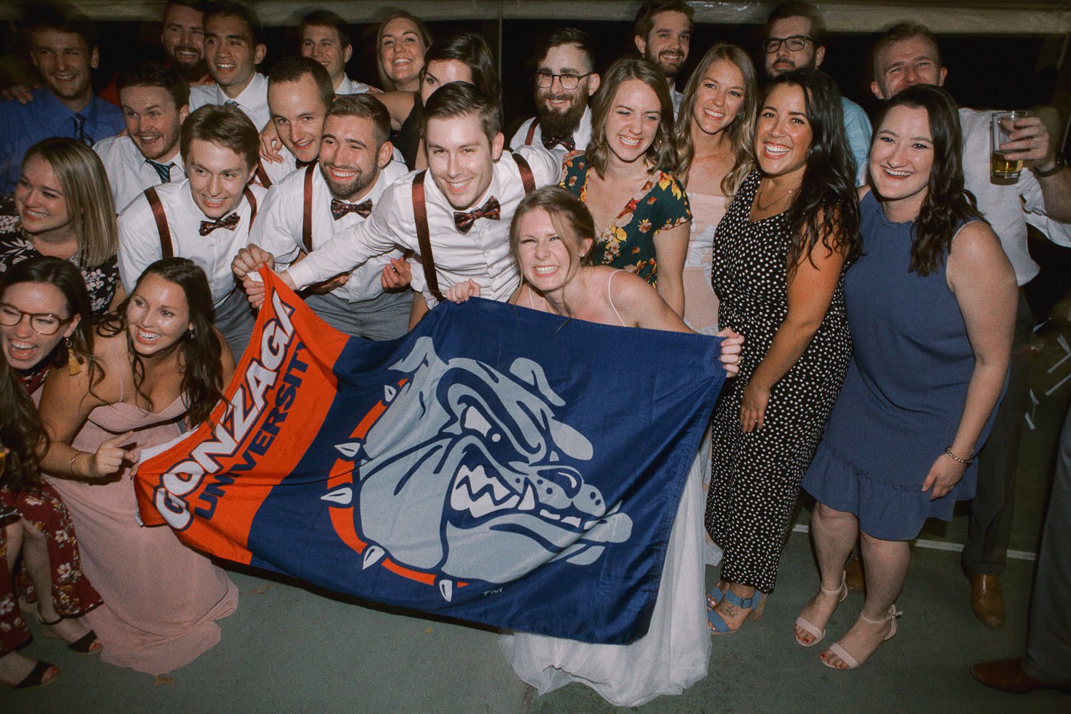  a group of college students hold a gonzaga flag while smiling 