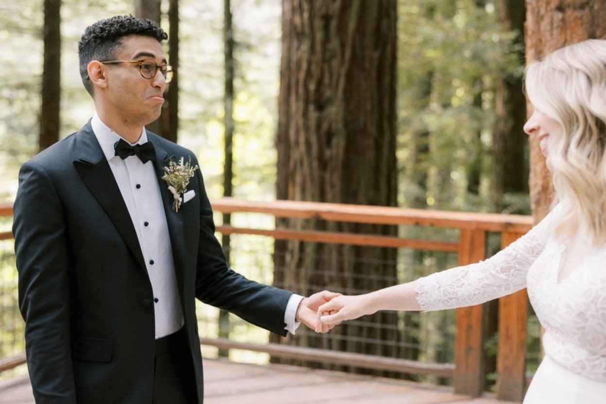  groom cries as he holds bride’s hand while they stand on the Redwood Deck at Hoyt Arboretum in Portland, Oregon 