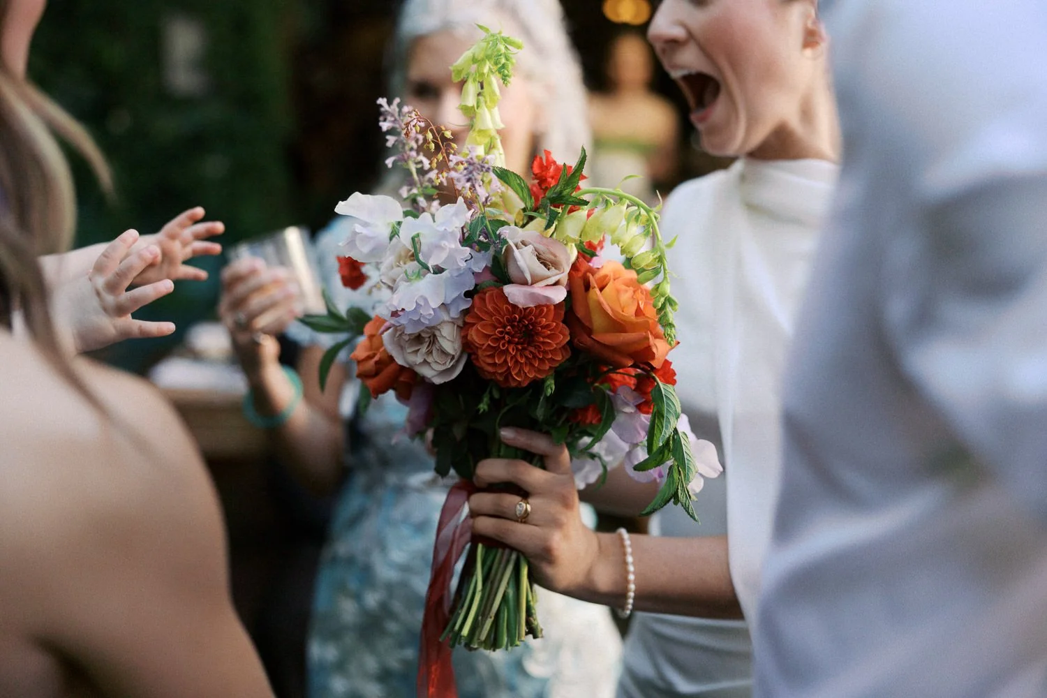 bride holding a bouquet while a baby reaches for it
