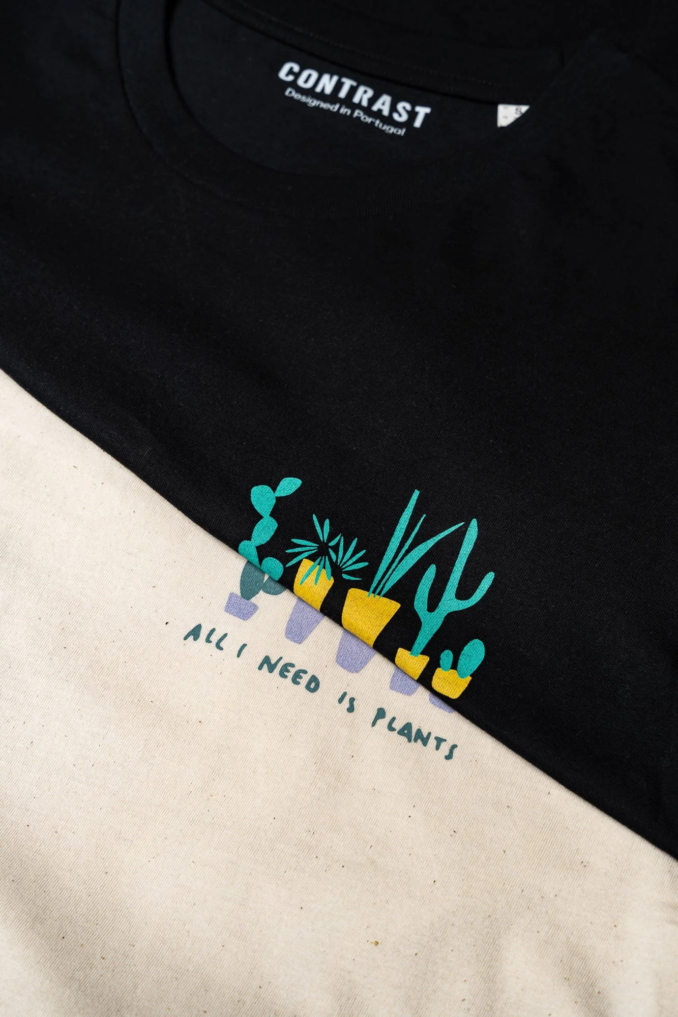 Close-up of Contrast organic cotton graphic tshirts with All I Need Is Plants design, sustainable minimalist streetwear in black and beige