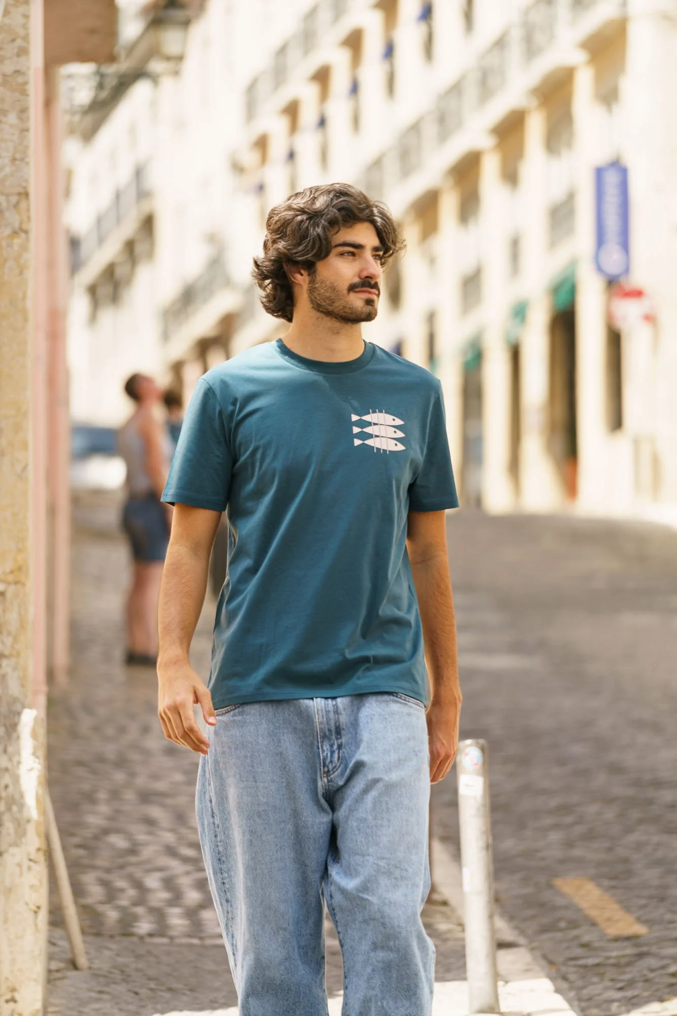 Man wearing Contrast organic cotton graphic designer tee in teal with sardine chest print, sustainable fashion streetwear shot
