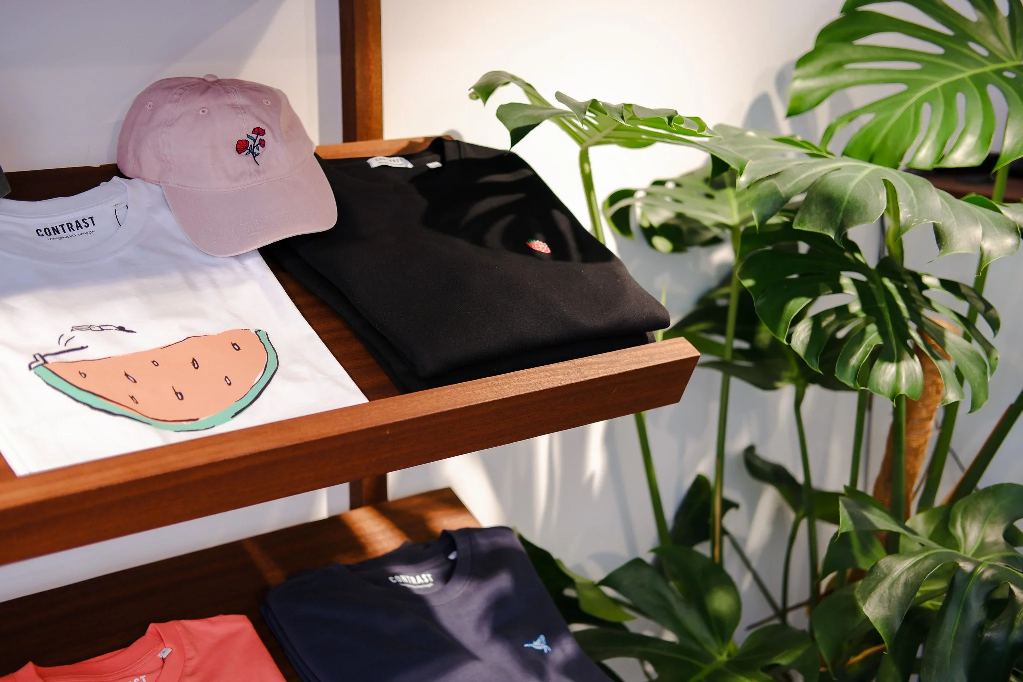 Display of Contrast organic cotton t-shirts with graphic and embroidered designs plus pink embroidered cap