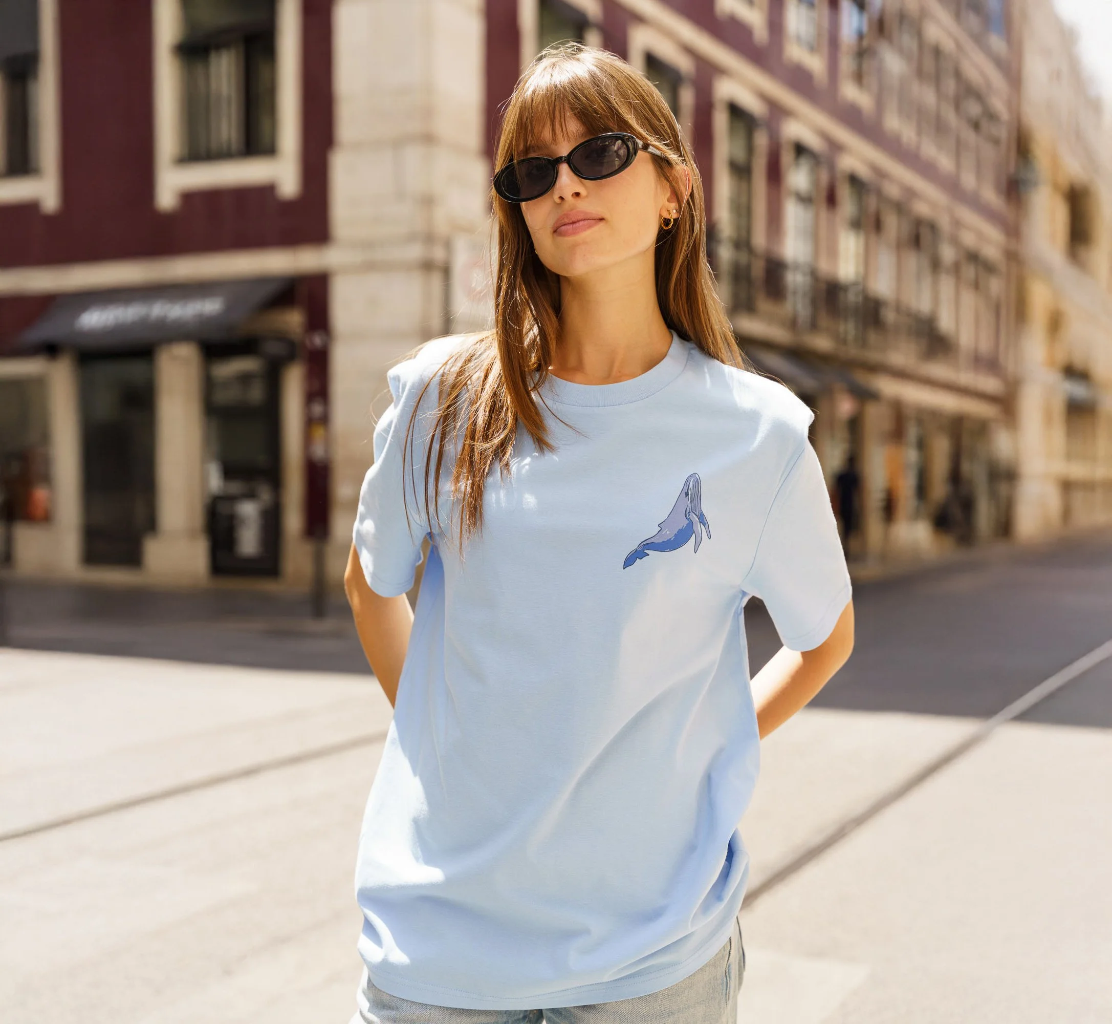 Woman wearing Contrast blue organic cotton graphic tee with embroidered bird design, sustainable minimalist streetwear.
