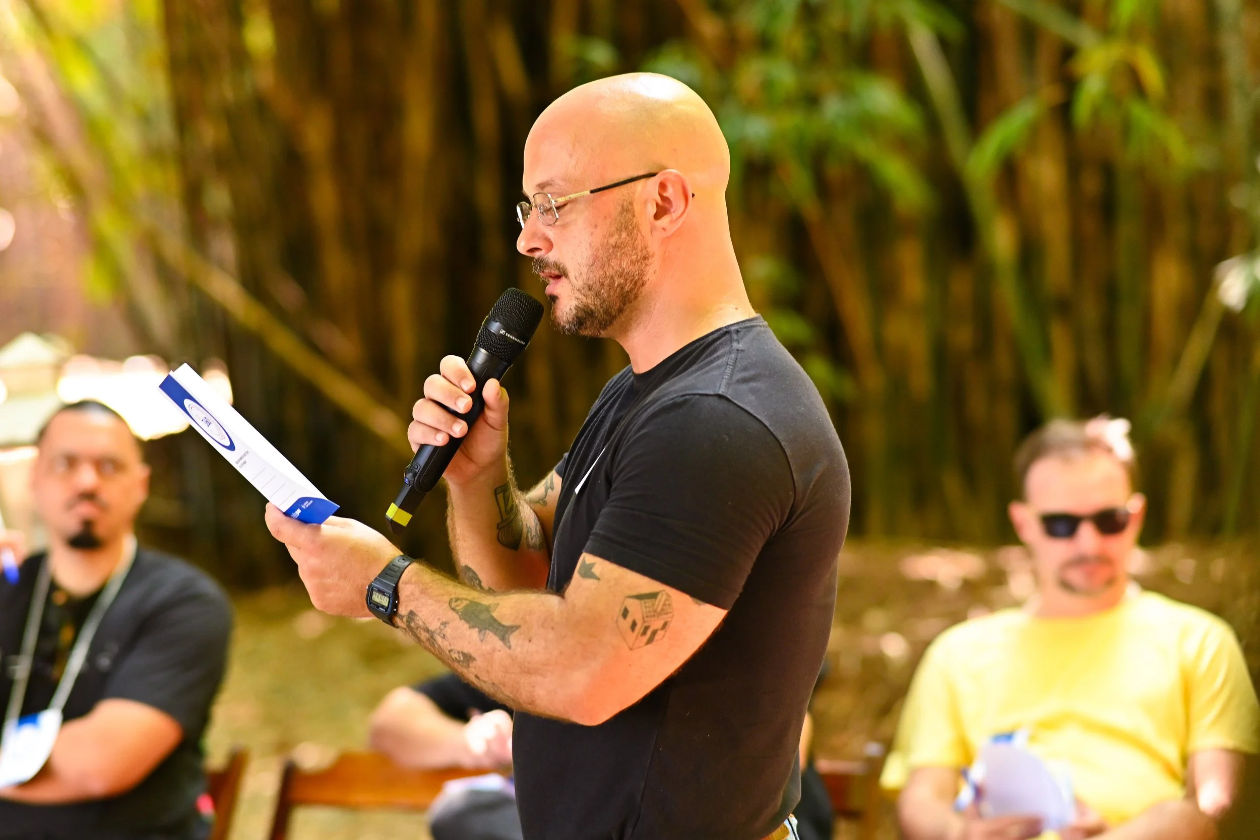 homem segurando um microfone e um folder em um evento. 