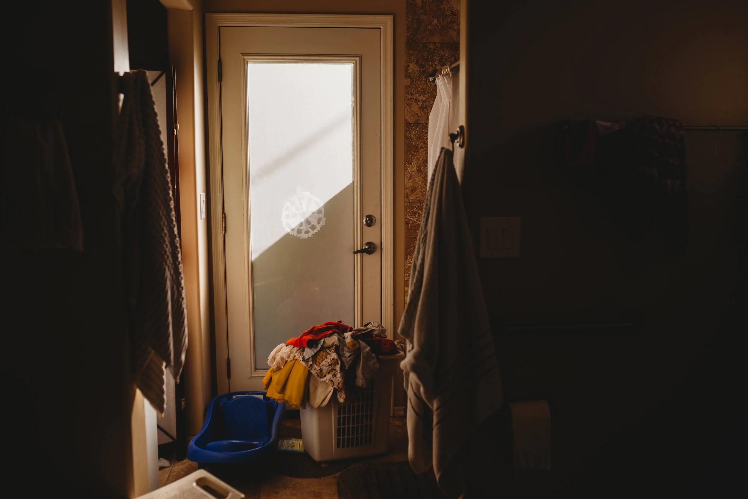Documentary family photography showing morning light on a pile of laundry, symbolizing the beauty of the mundane.