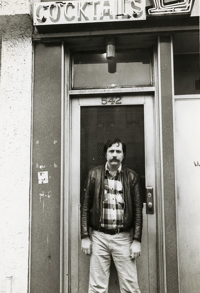 Lester Bangs beneath cocktails sign