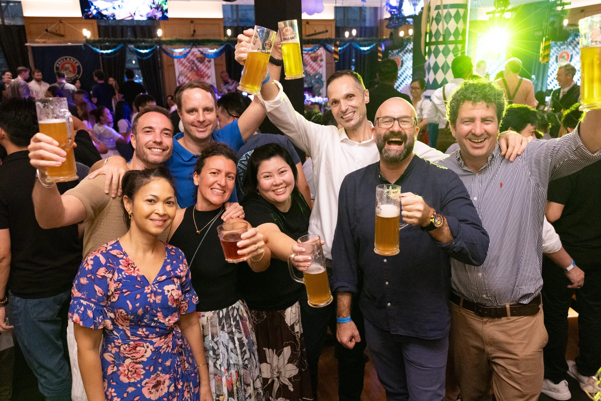  Staged group portrait of guests celebrating with beer mugs at Paulaner Bräuhaus Oktoberfest 