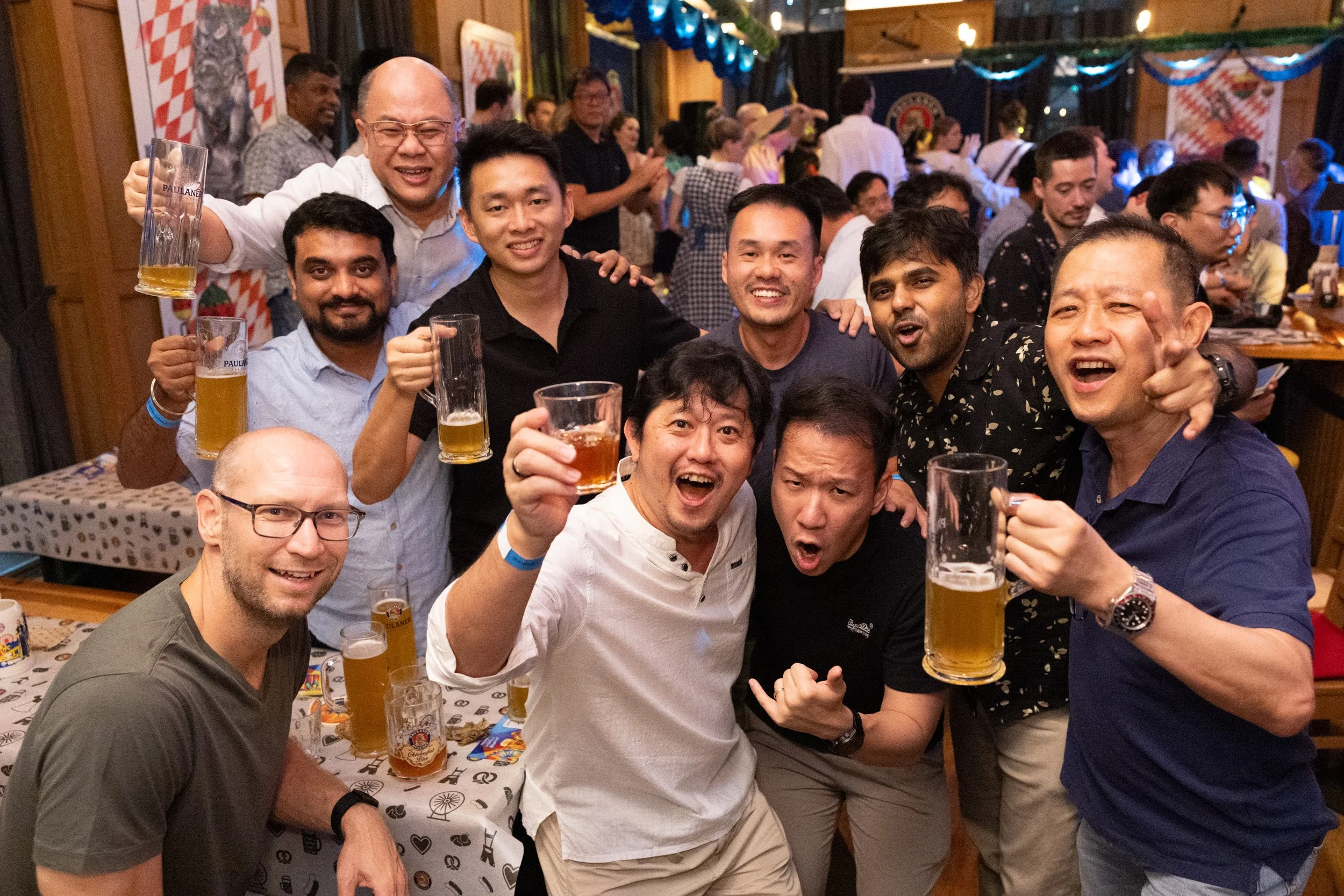  Group of corporate guests posing with German beer mugs at Paulaner Bräuhaus event 