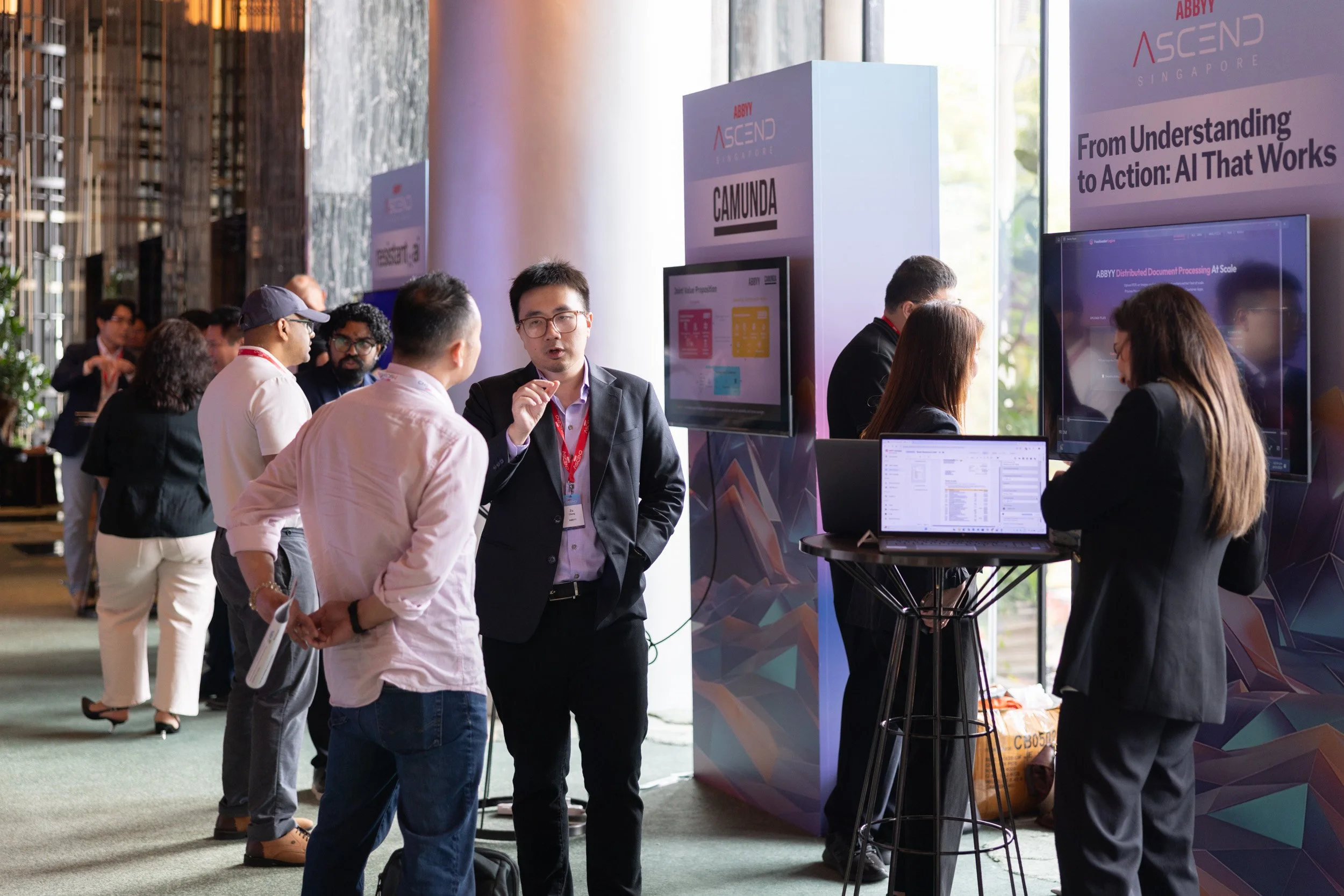  ABBYY staff demonstrating software solutions to attendees in the exhibition foyer at PARKROYAL COLLECTION Pickering. 