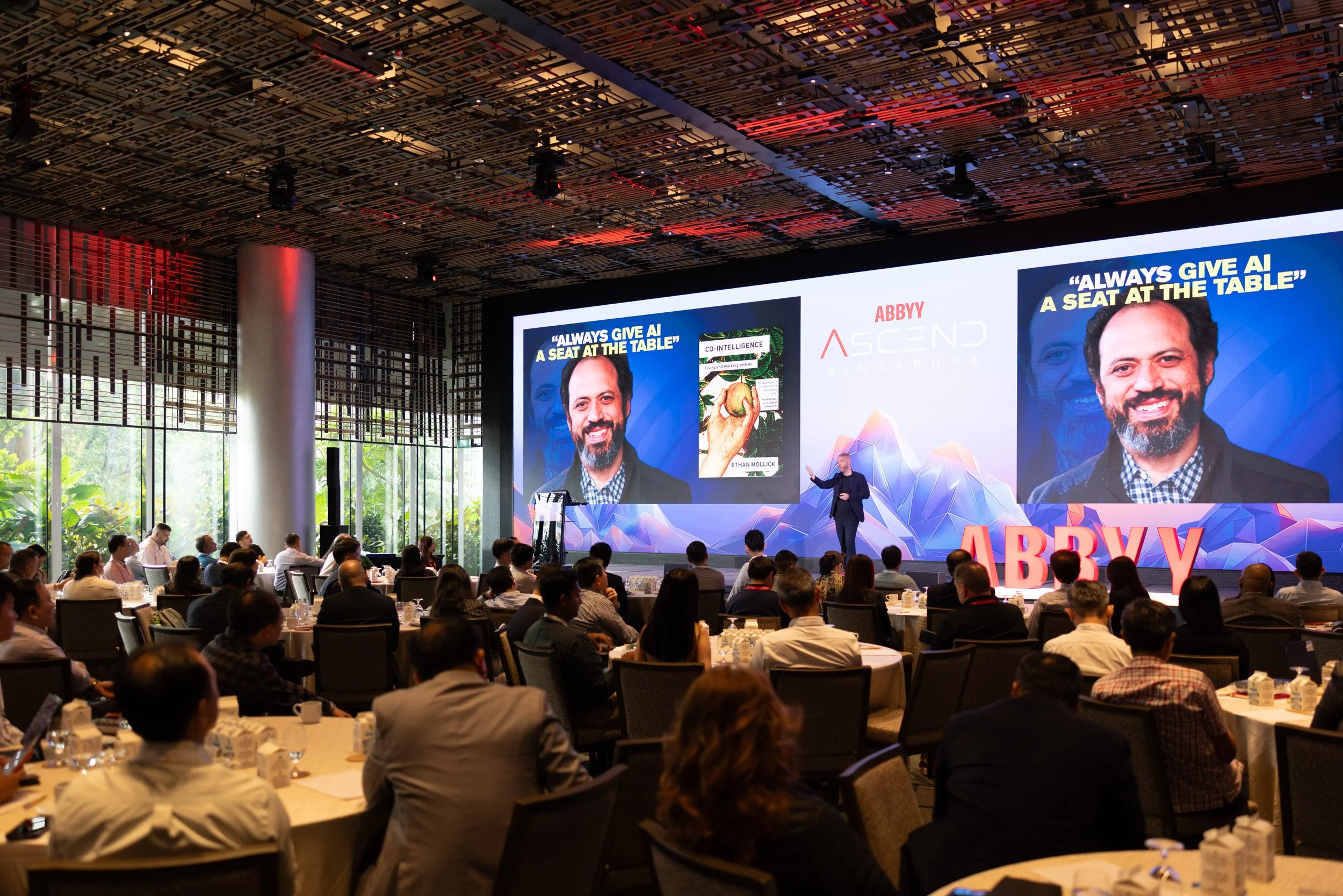  Ballroom view showing attendees seated facing the stage with speaker Dado van Peteghem. 