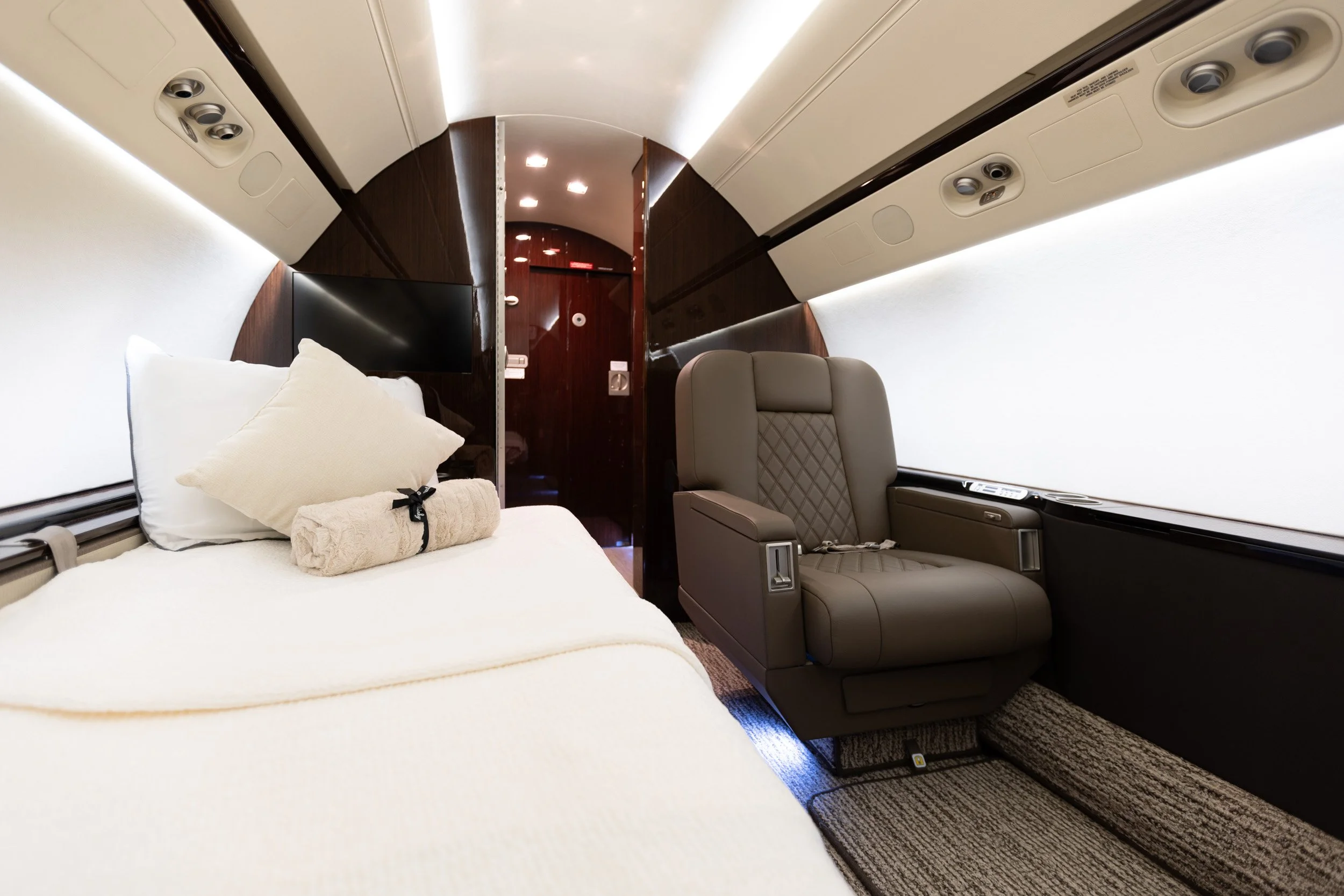  Custom bed configuration and plush leather seating inside a Jet Aviation private jet cabin. 
