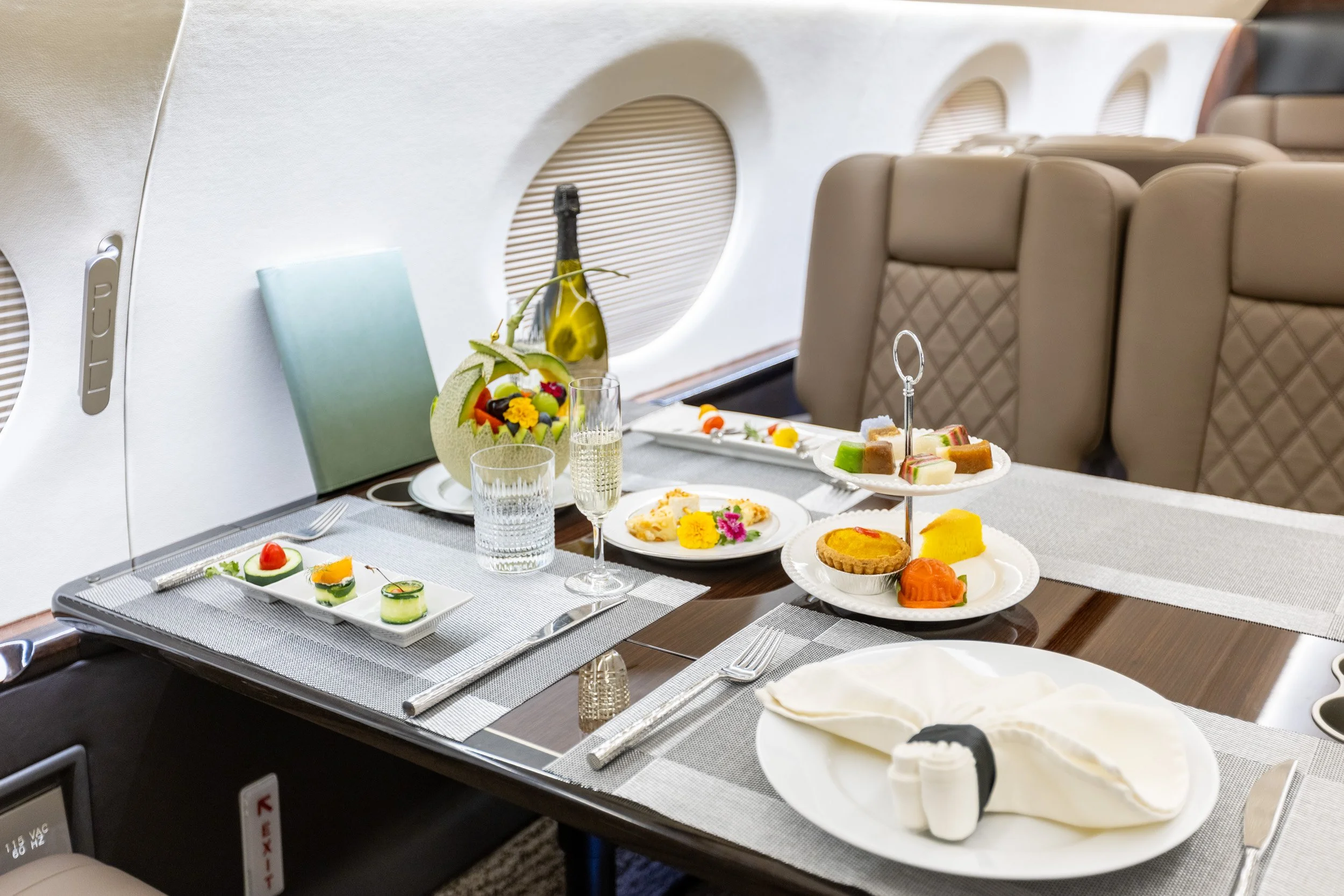  Inflight fine dining setup on a luxury private jet table featuring wine and local pastries. 
