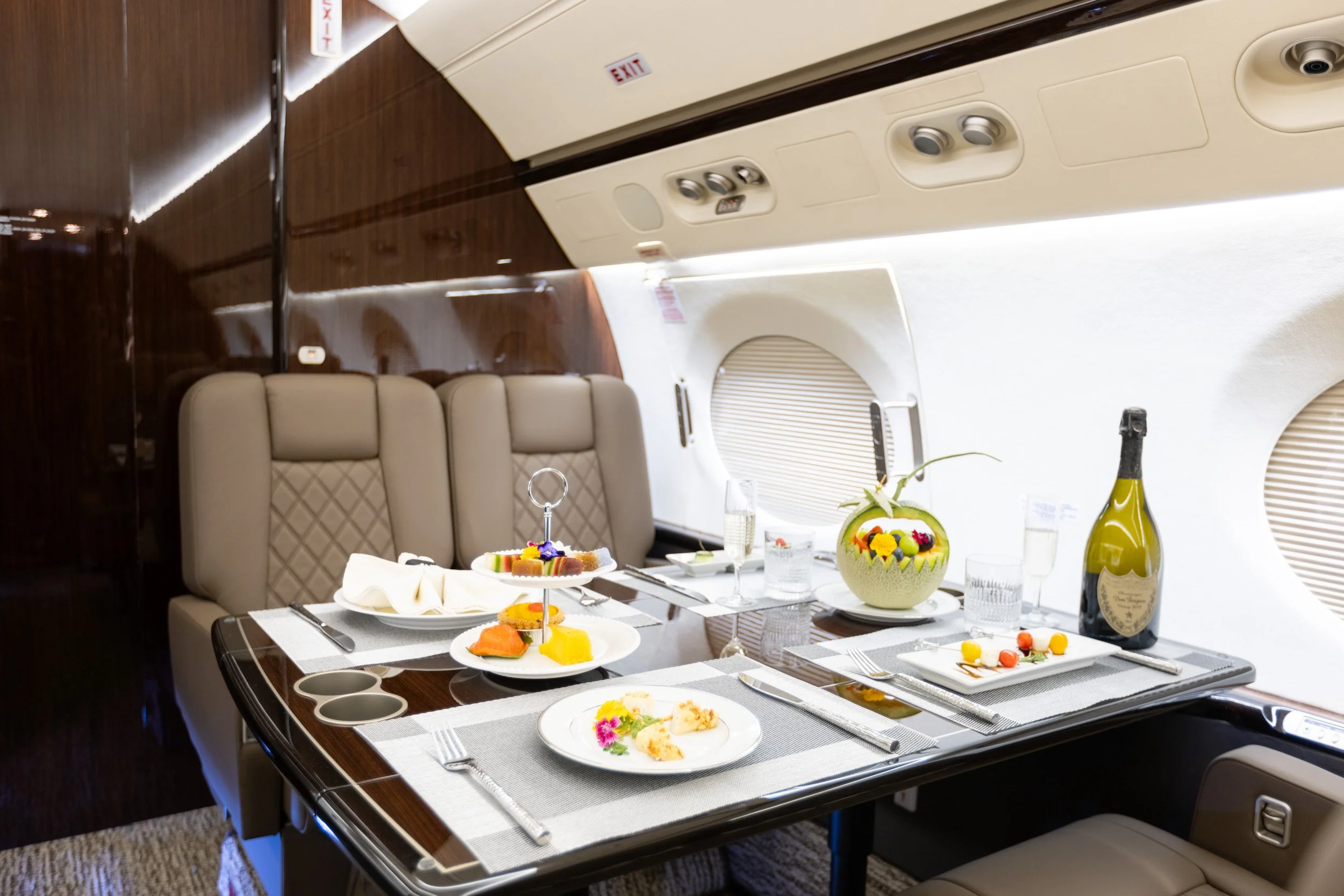  Premium inflight dining table arrangement with local pastries and wine inside a private jet. 