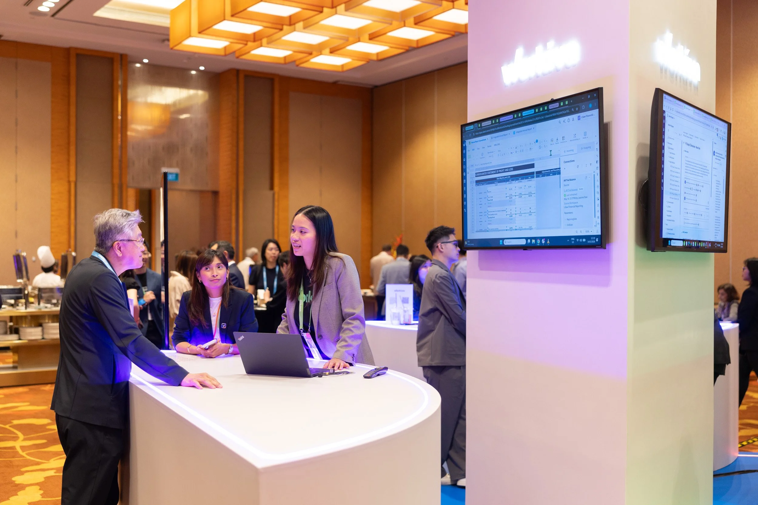 Workiva staff engaging with an event visitor at the exhibition booth in Sands Expo. 