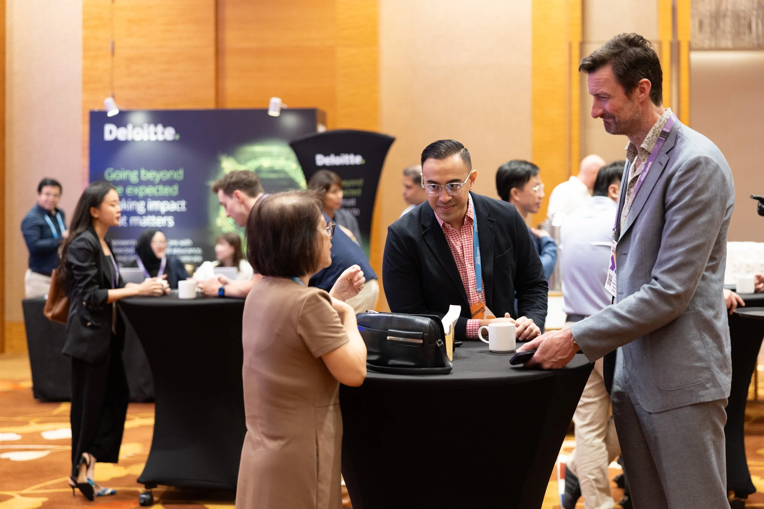  Business professionals networking near the Deloitte exhibition booth at Workiva Accelerate Asia. 