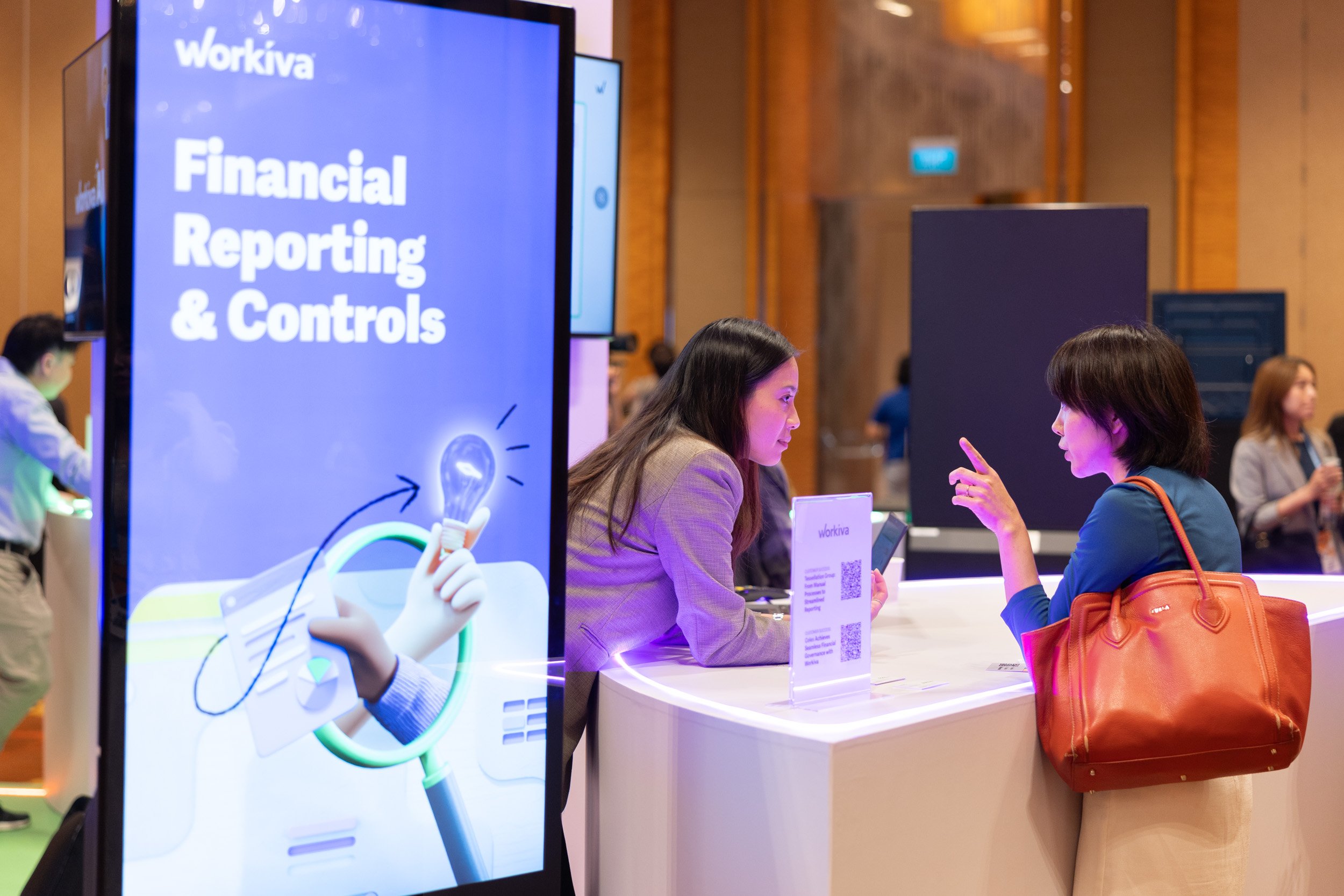  Representative interacting with an event guest at the branded Workiva booth. 