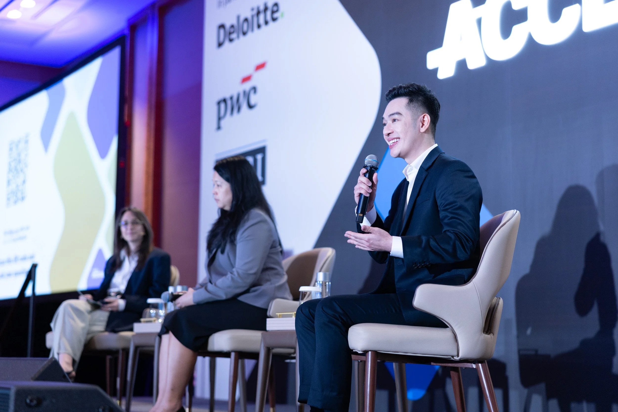  Speaker Benjamin Wong presenting on stage alongside panelists Alyssa Zucker and Dr. Lee Hui Mien. 