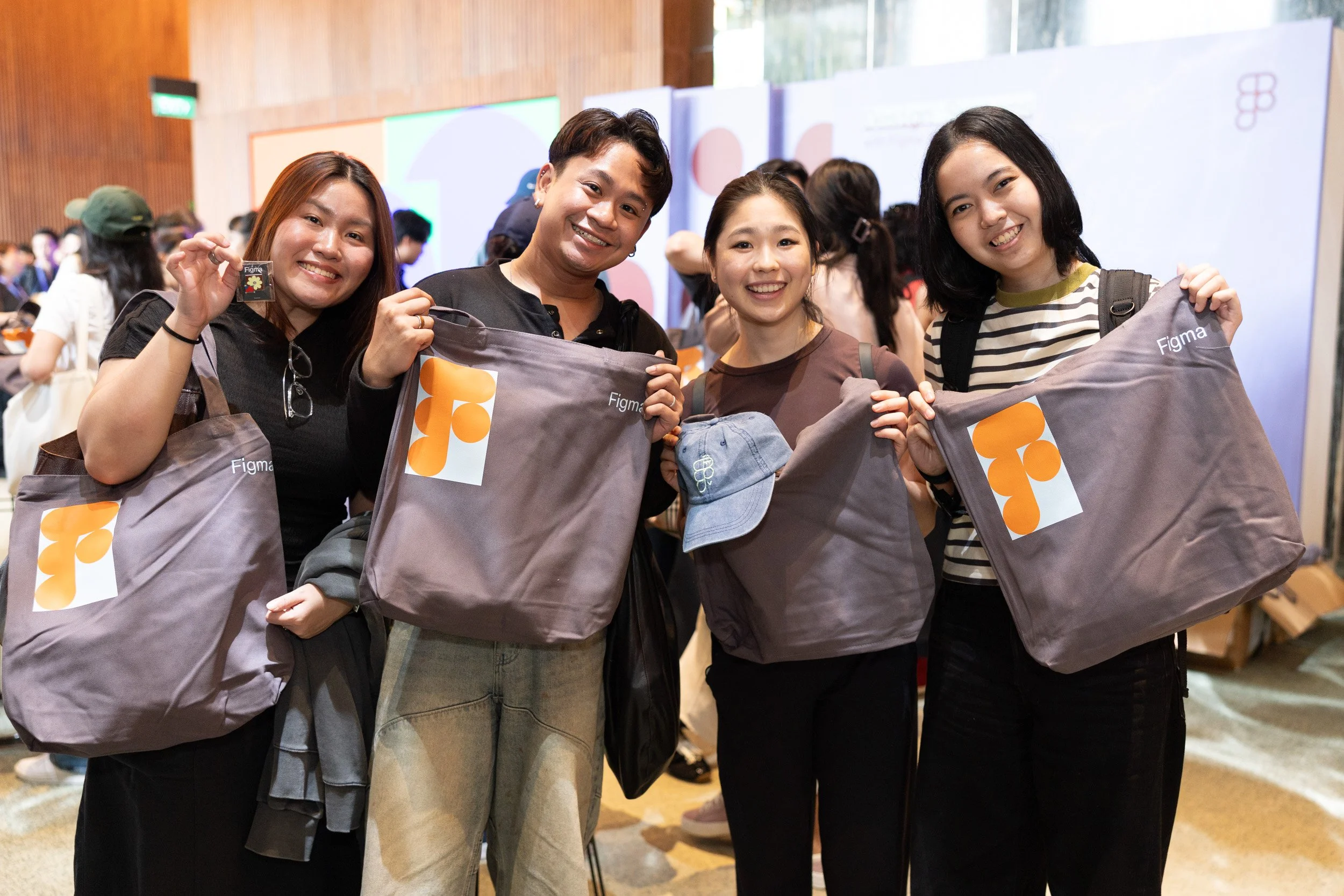  Four event attendees posing for a group photo while showcasing Figma goodie bags. 