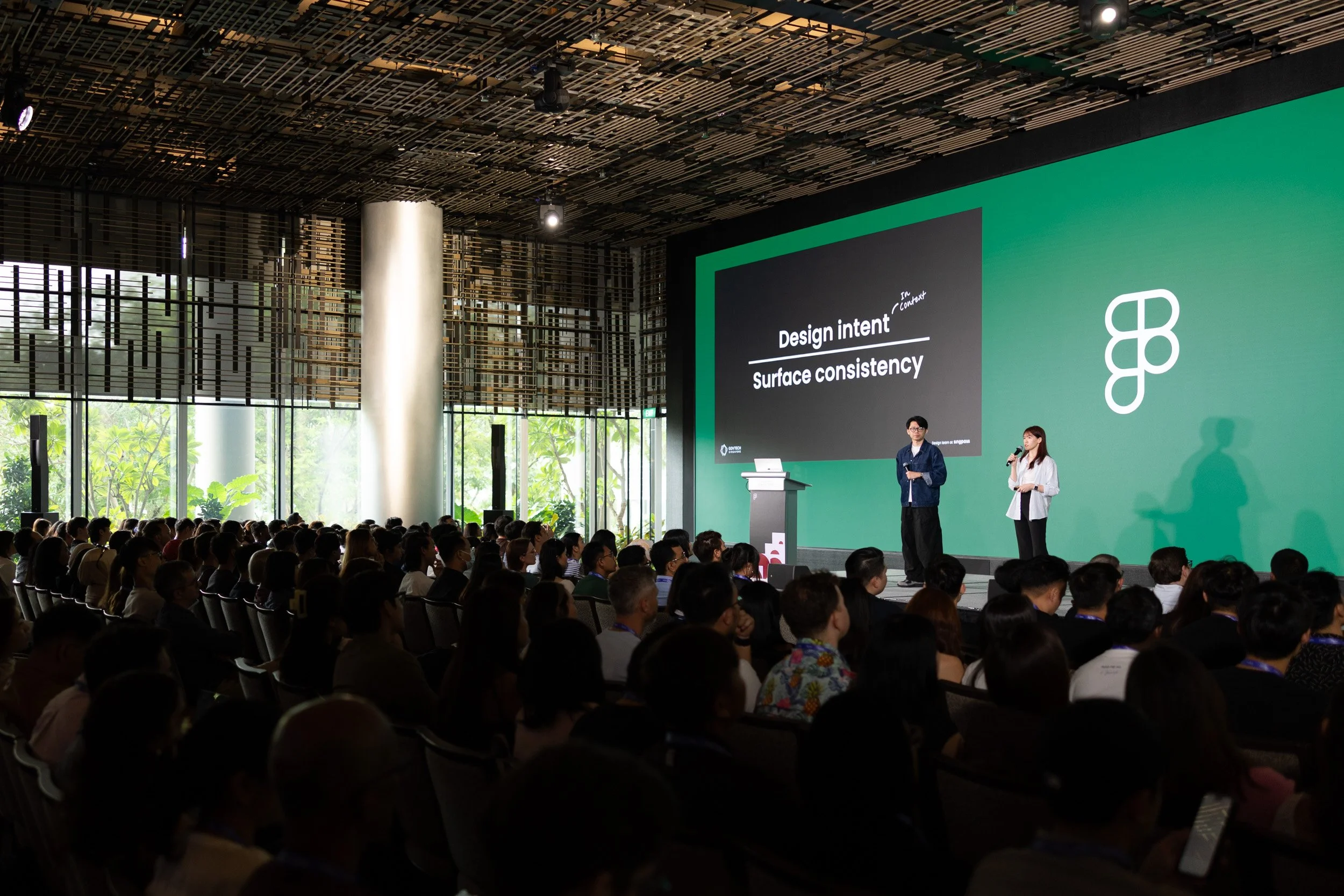  Wide angle stage photo of co-presenters Edwin Lau and Evelyn Ng speaking together. 