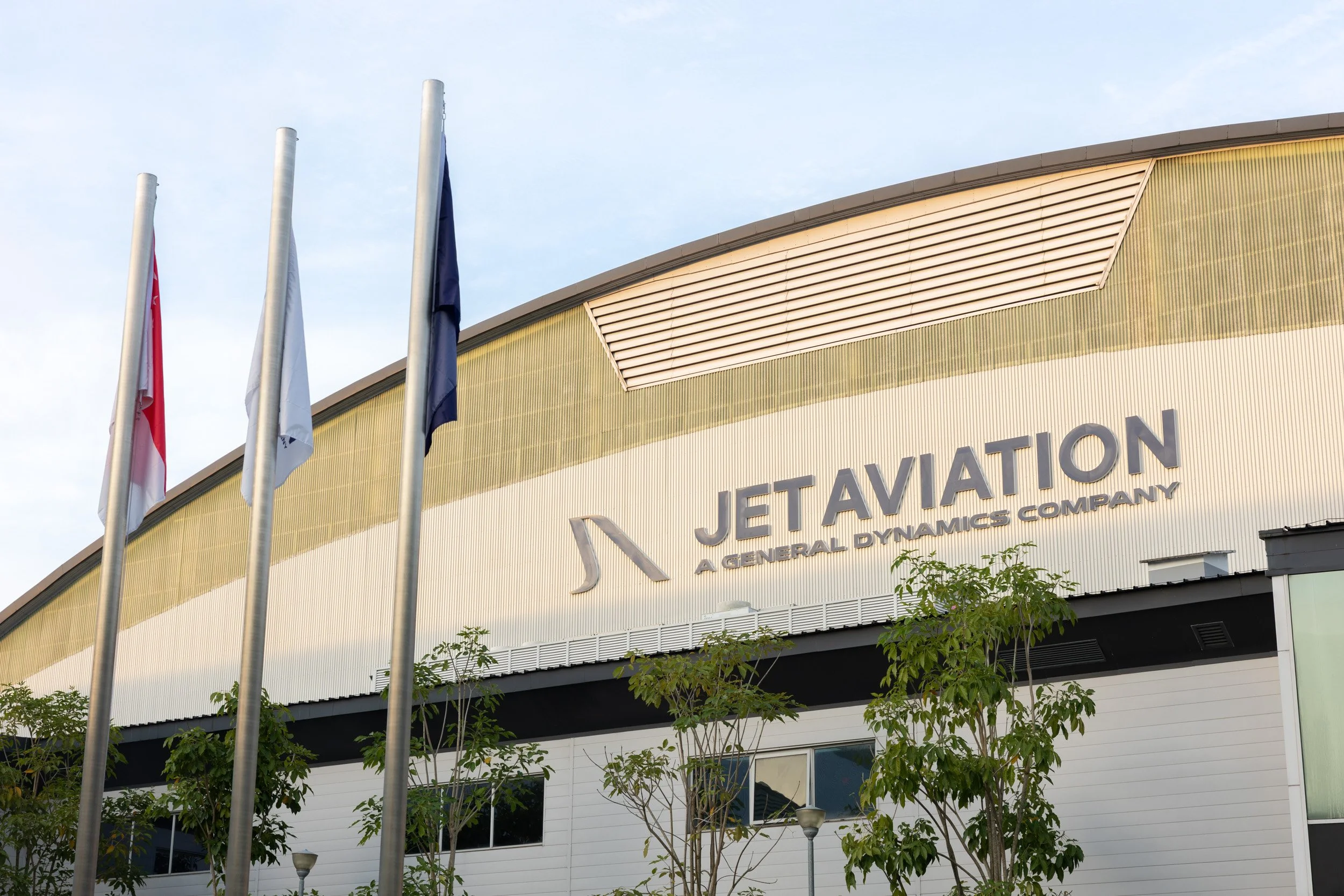  Exterior architectural photography of the Jet Aviation Singapore facility entrance featuring company logo and flags. 