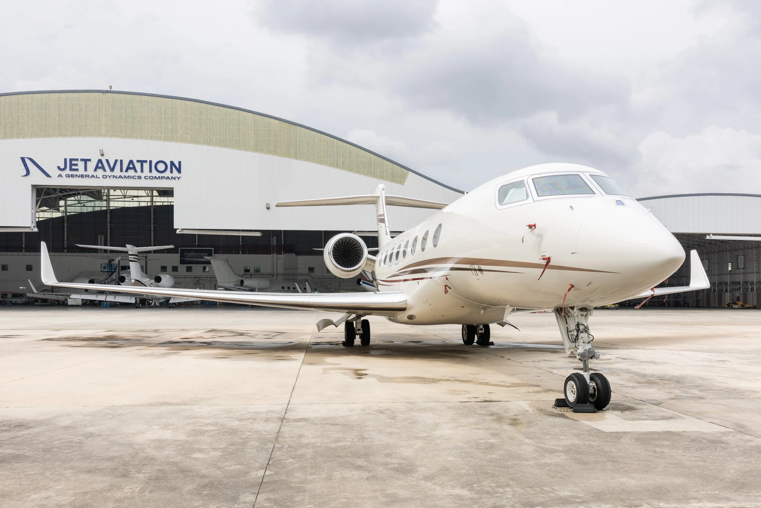  Private corporate jet parked on the wet tarmac outside Jet Aviation Seletar Airport hangar. 