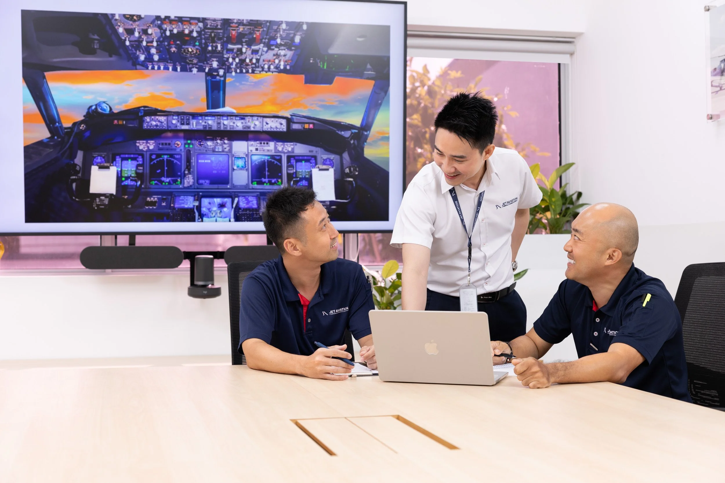  Jet Aviation corporate staff collaborating in a presentation room with flight deck visuals projected on screen. 