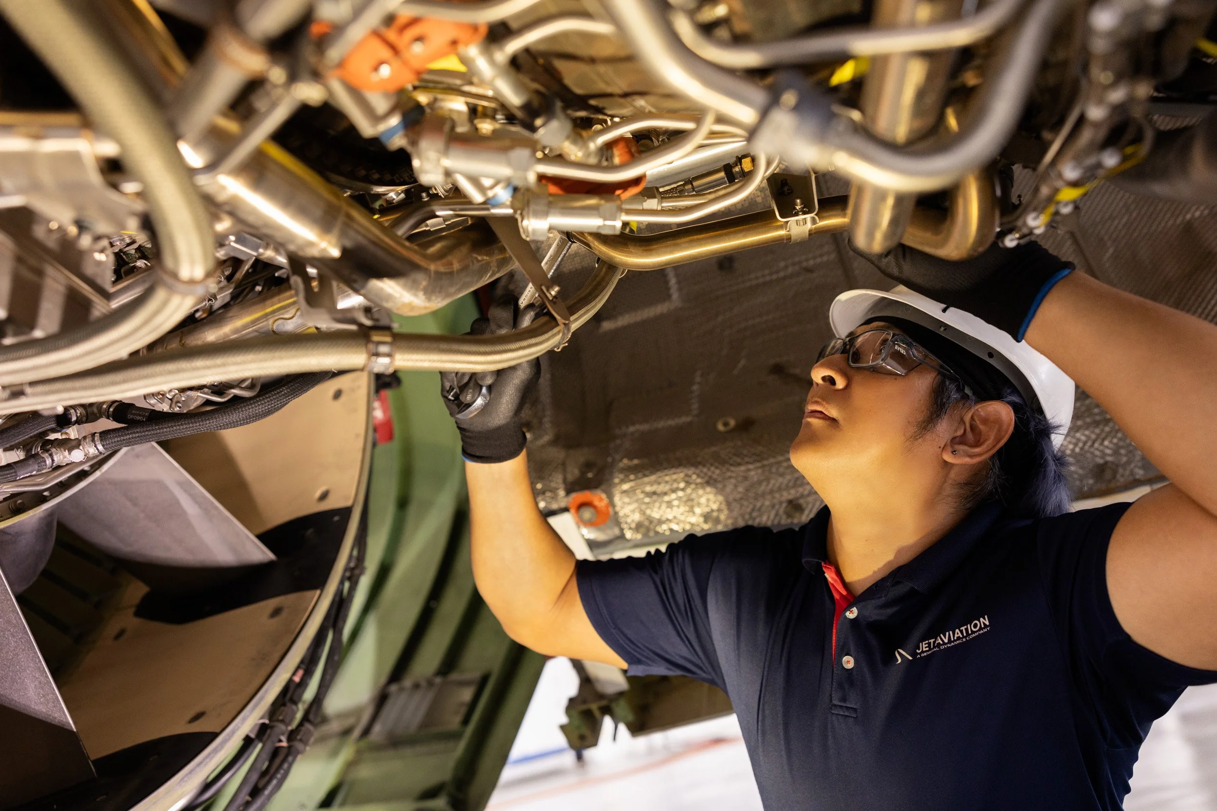  Aviation maintenance technician inspecting a jet engine from below inside the Jet Aviation hangar. 