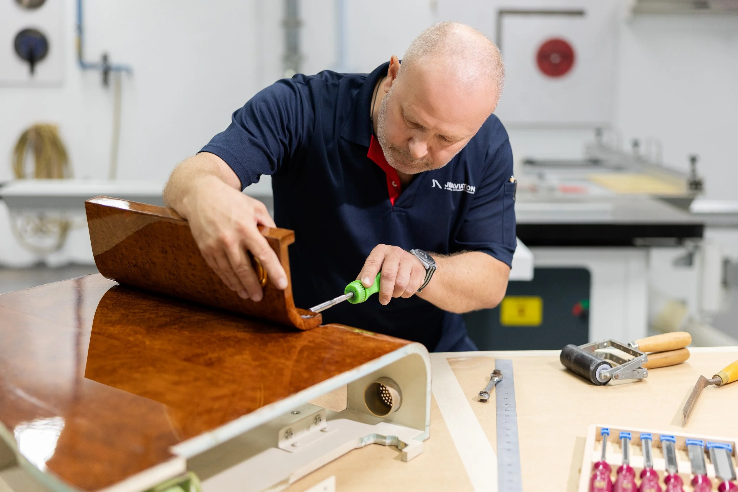  Jet Aviation craftsman hand-crafting custom wood interior panels for luxury aircraft cabin fitting. 