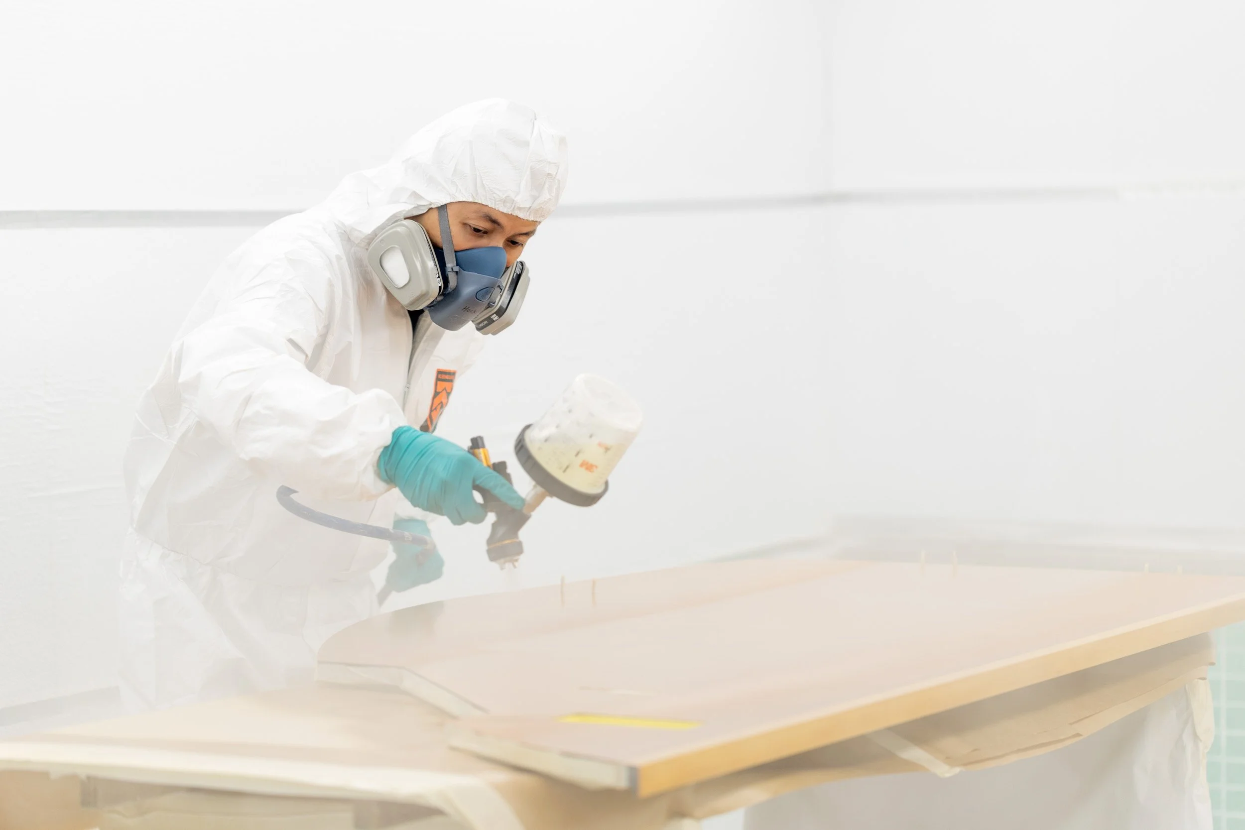  Detailed close-up of aircraft technician in full protective gear precision-spraying aviation components. 