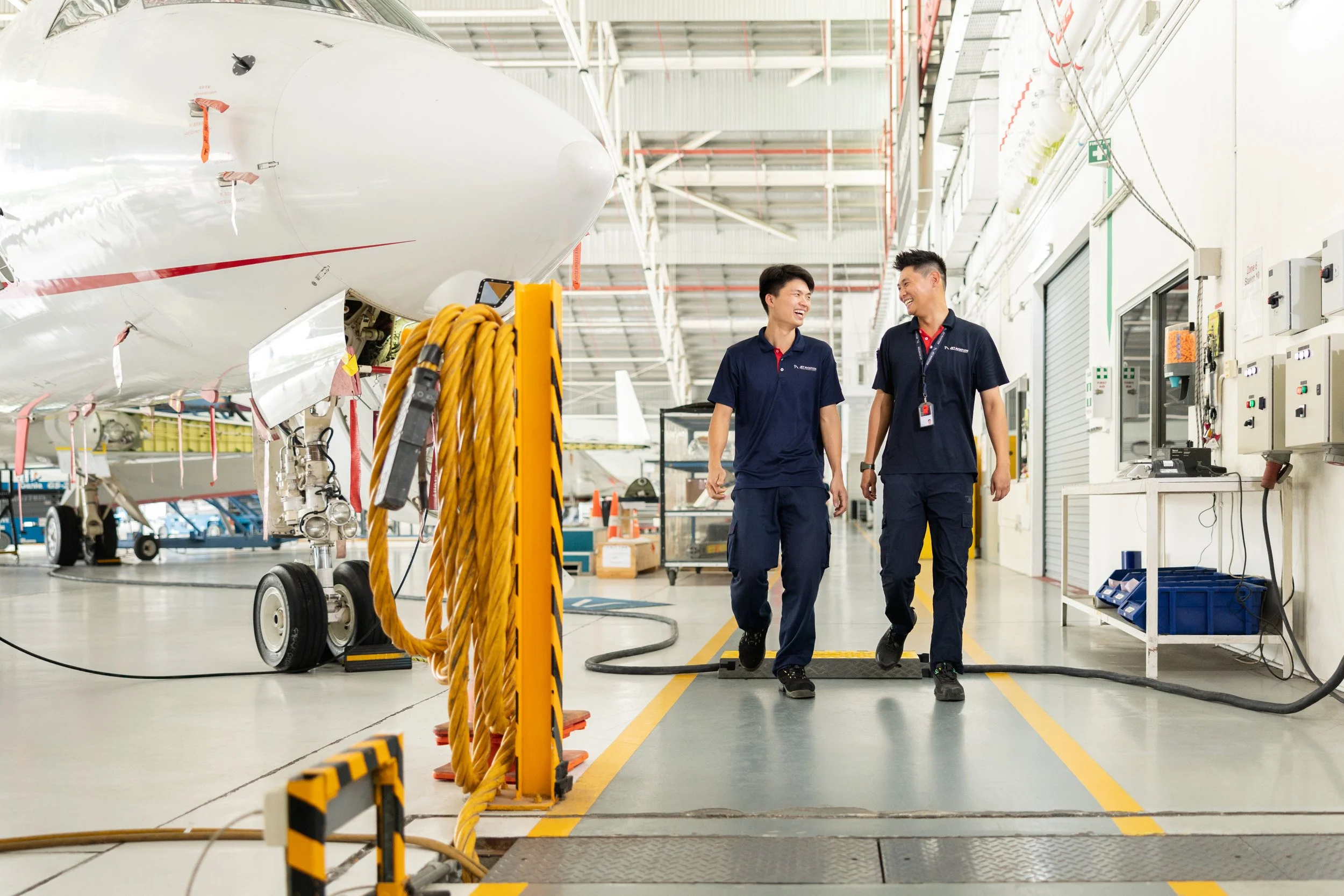  Two Jet Aviation operational staff discussing flight logistics while walking through the aircraft hangar. 