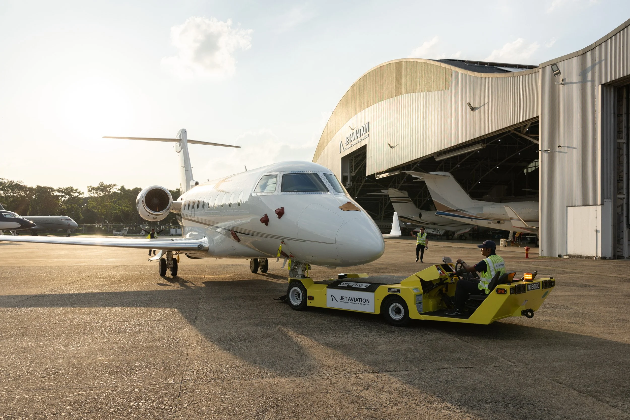 Ground handling crew and operations staff towing a private jet across the Seletar airfield apron. 