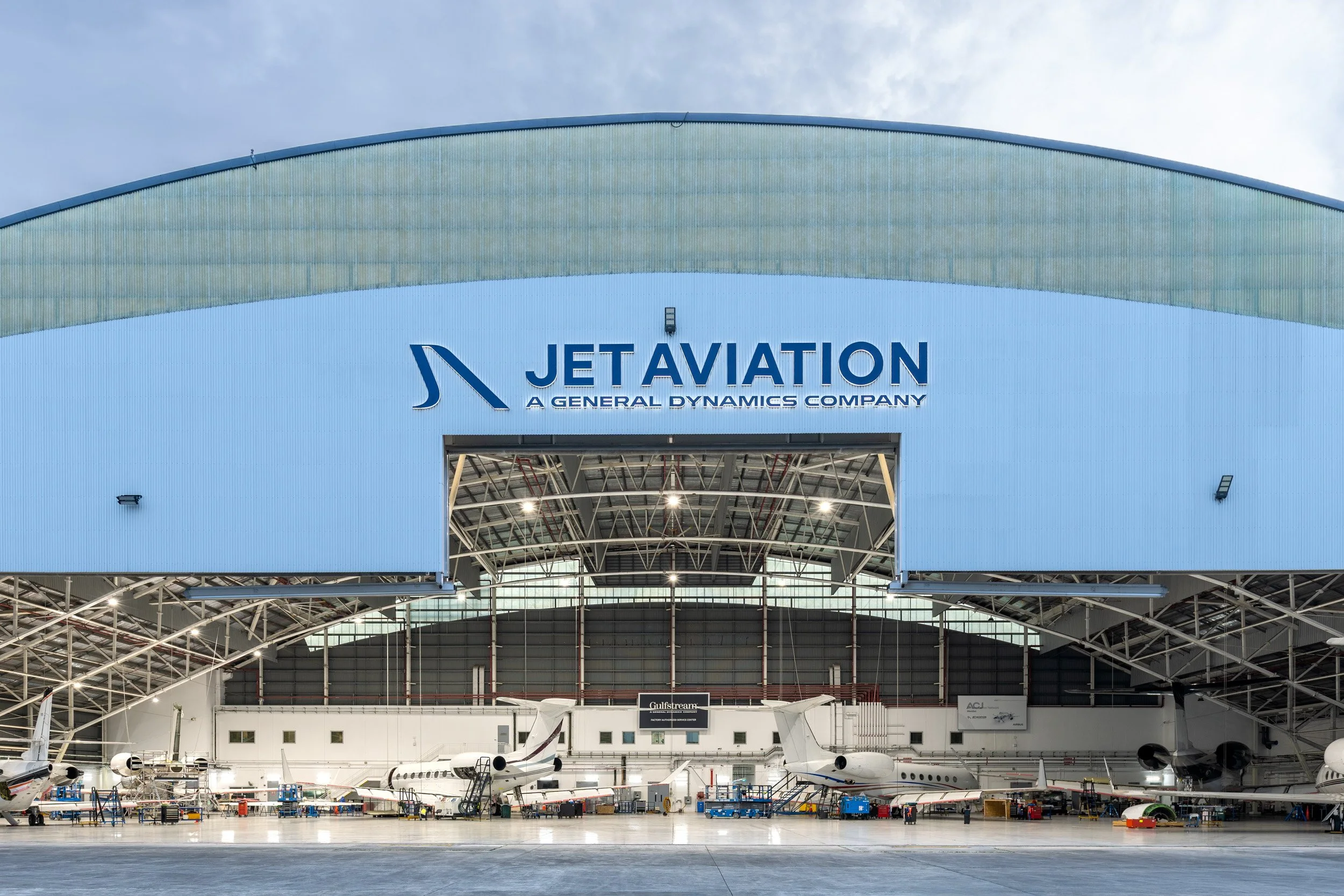  Exterior architectural shot of Jet Aviation hangar illuminated at blue hour twilight. 