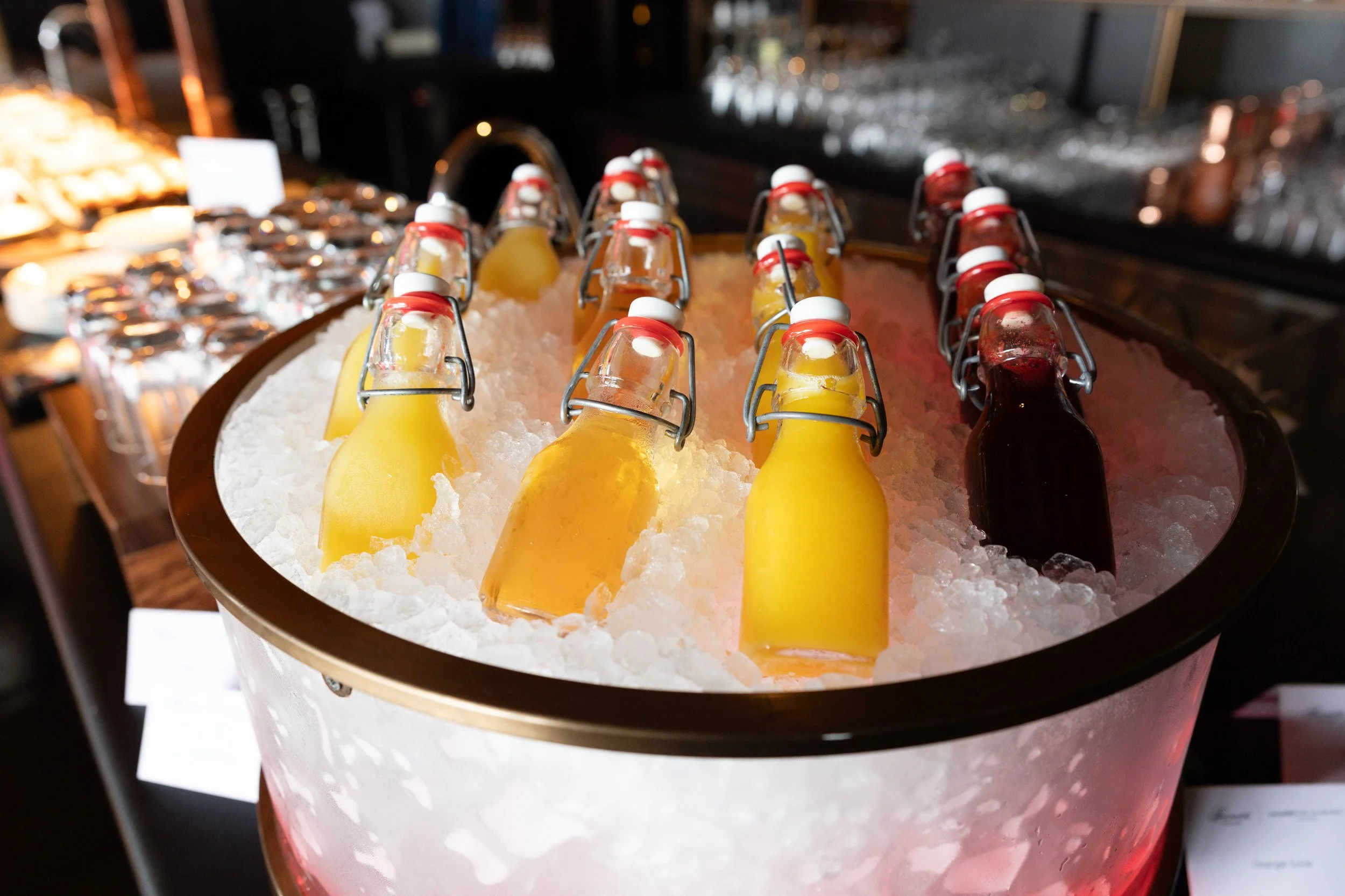  Chilled fruit juices served on ice with catered event refreshments in the background. 