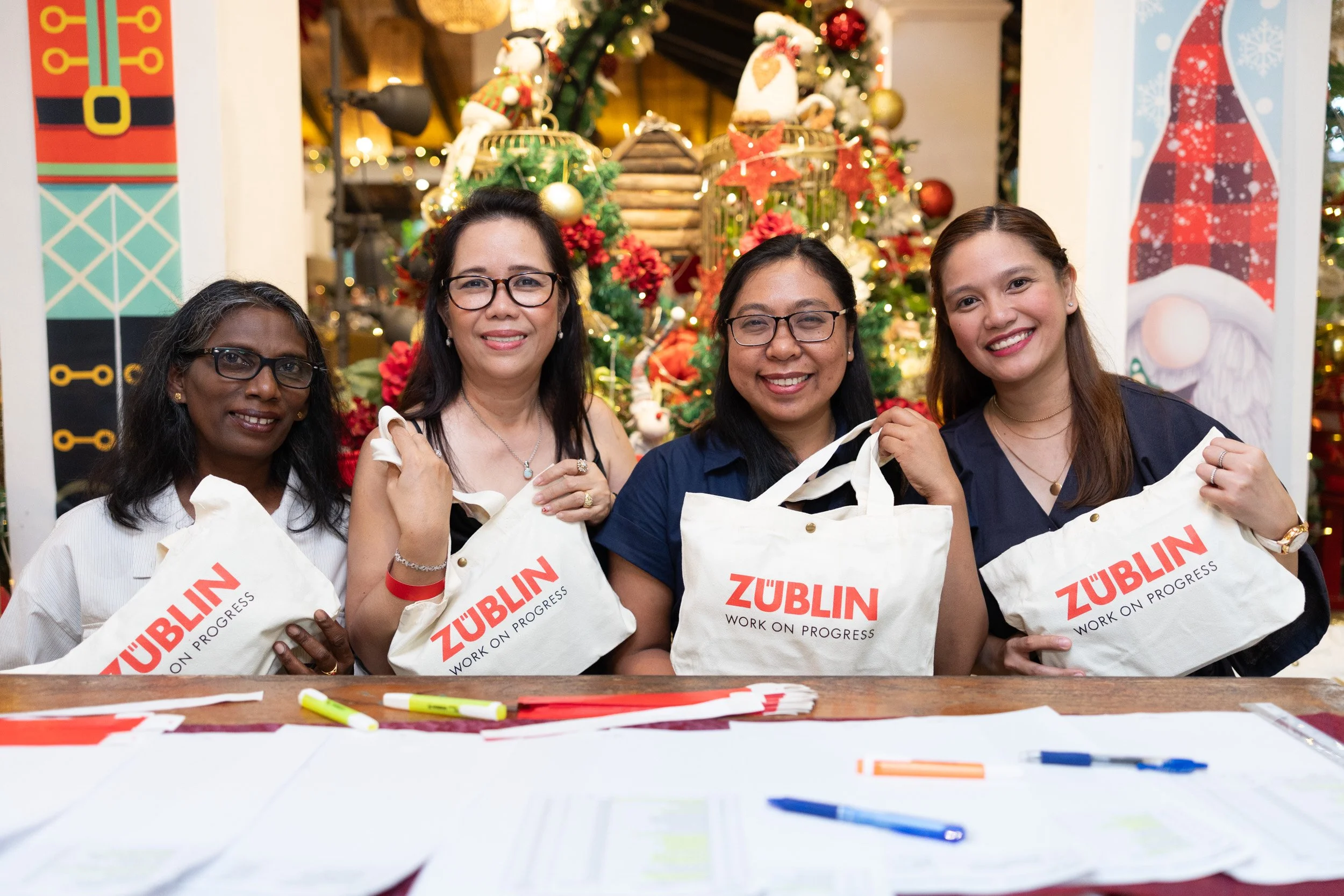  Posed group portrait of Züblin reception staff holding corporate event gift bags for arriving guests. 