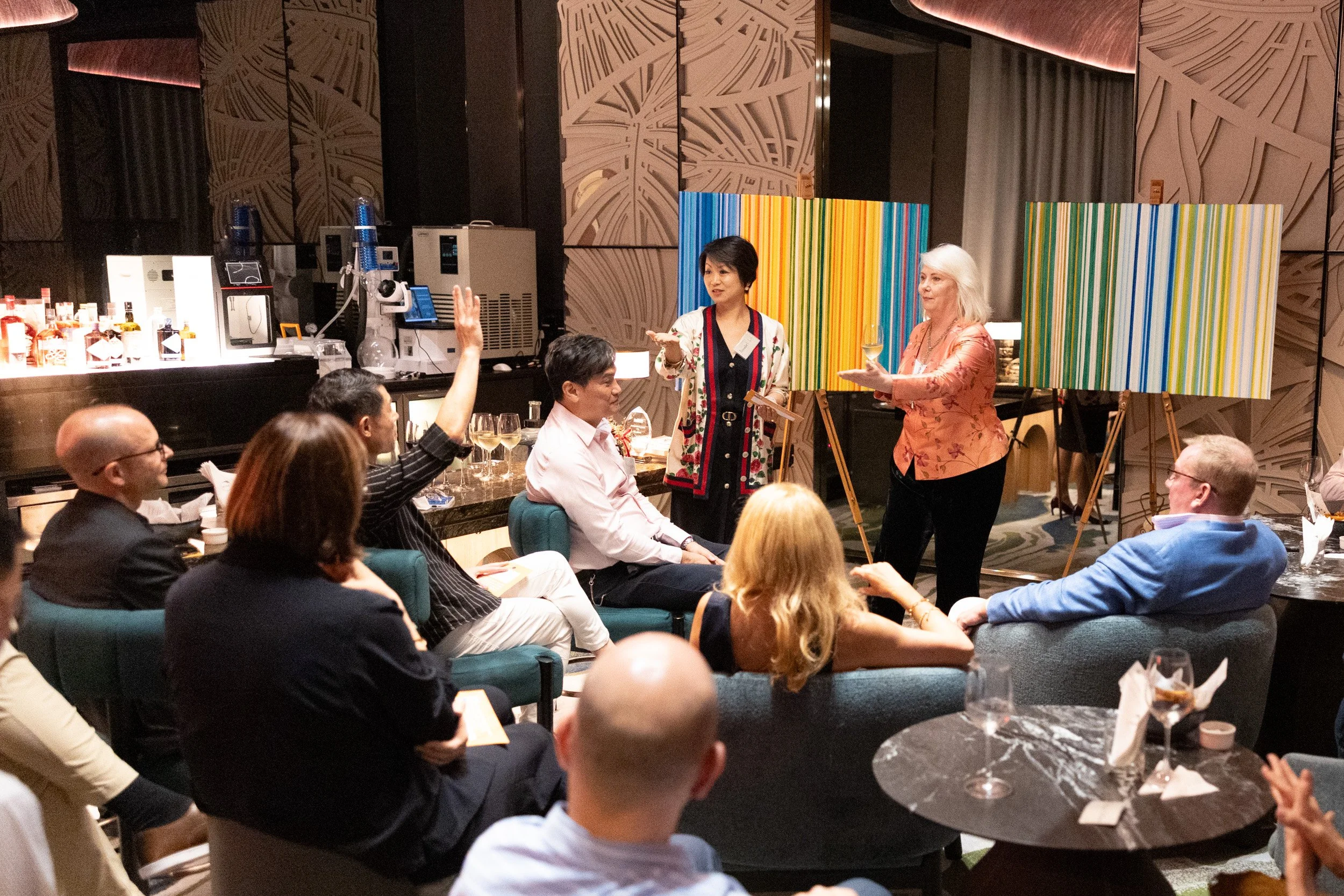  Wide perspective of co-hosts Joanne Flinn and Annabel Lin speaking to guests during the book relaunch. 