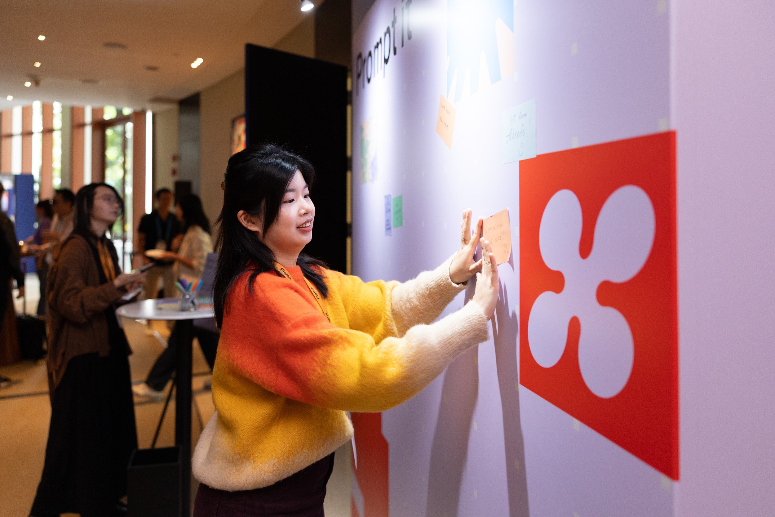 Event attendee placing a handwritten note on the interactive Figma community message wall. 