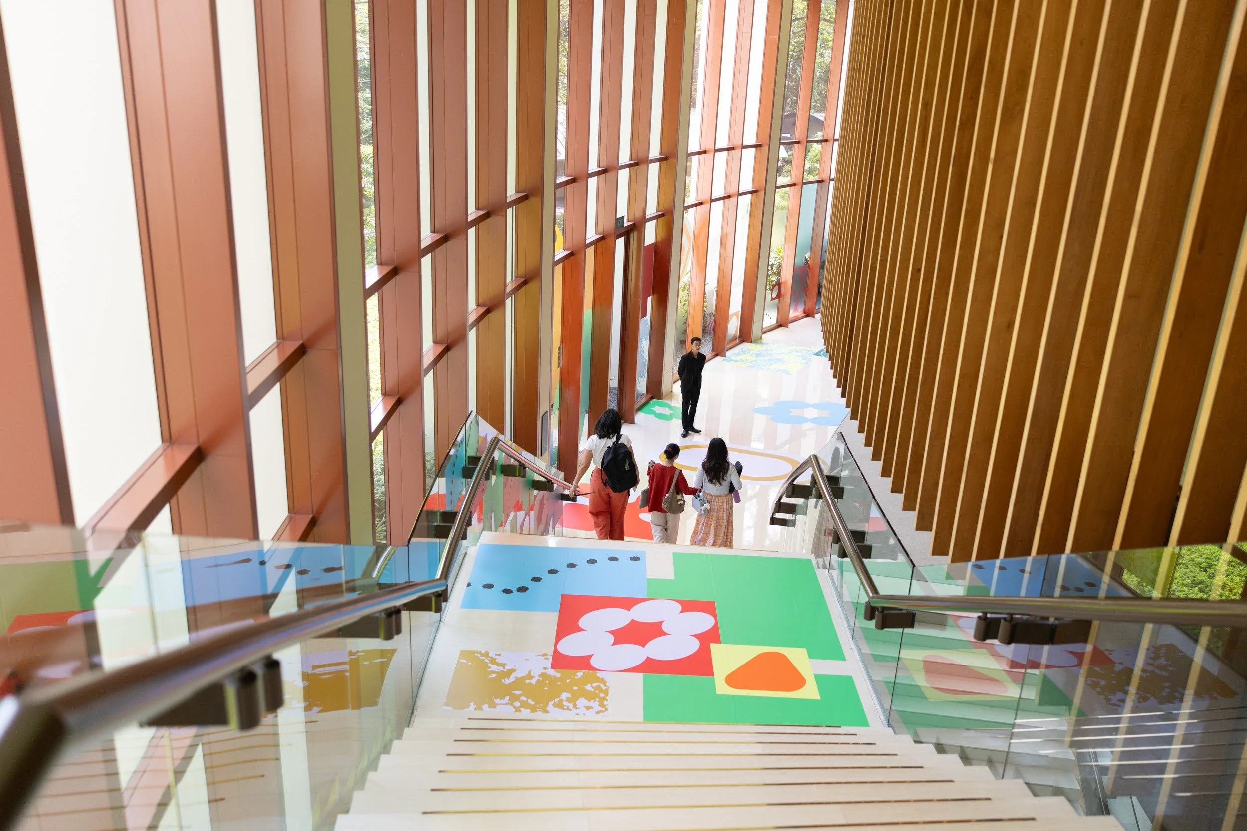  Guests descending grand staircase featuring custom Figma brand artwork leading to the Capella Grand Ballroom. 