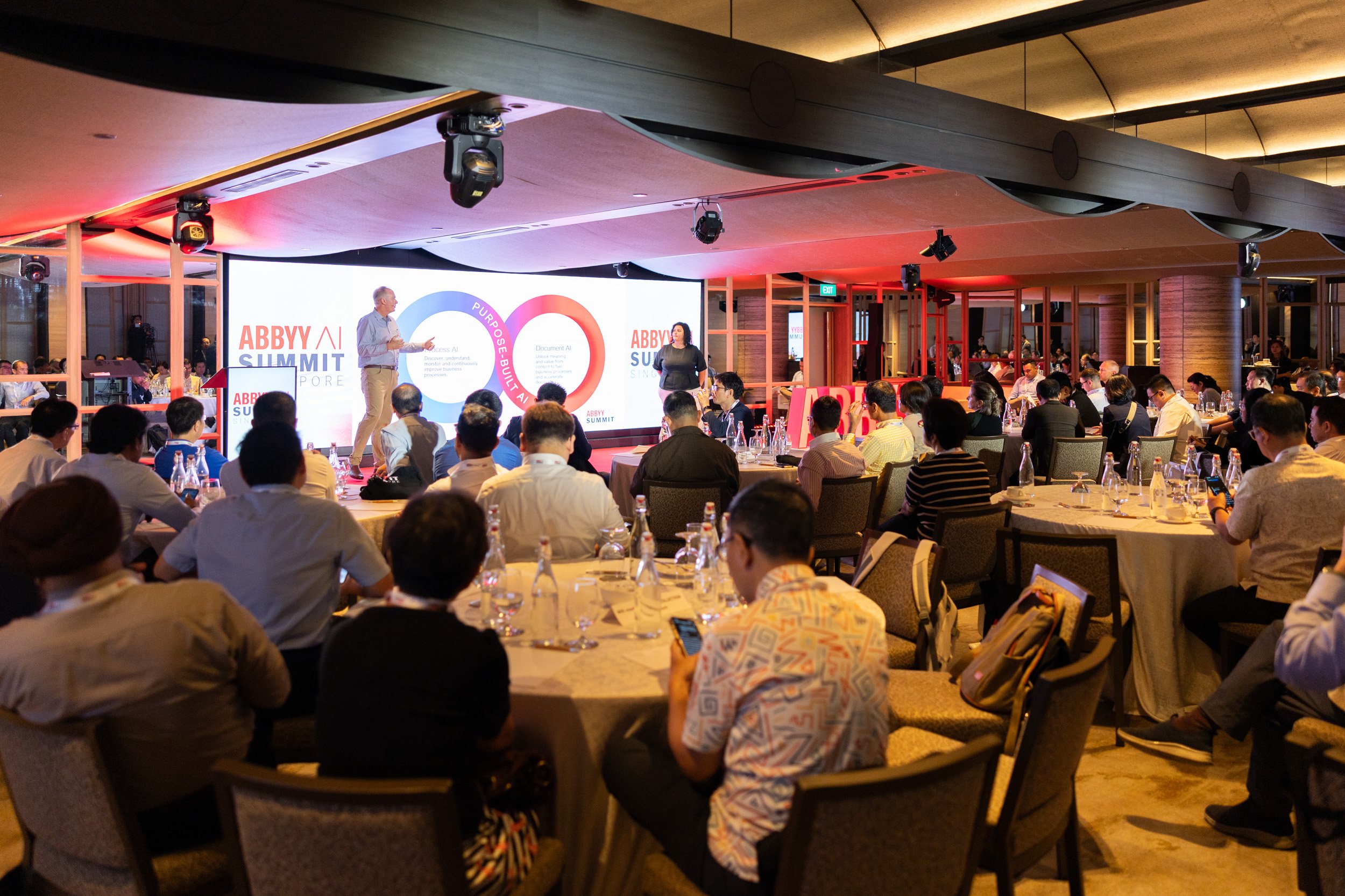  Wide stage photograph of co-presenters Slavena Hristova and Jon Knisley addressing the summit audience. 
