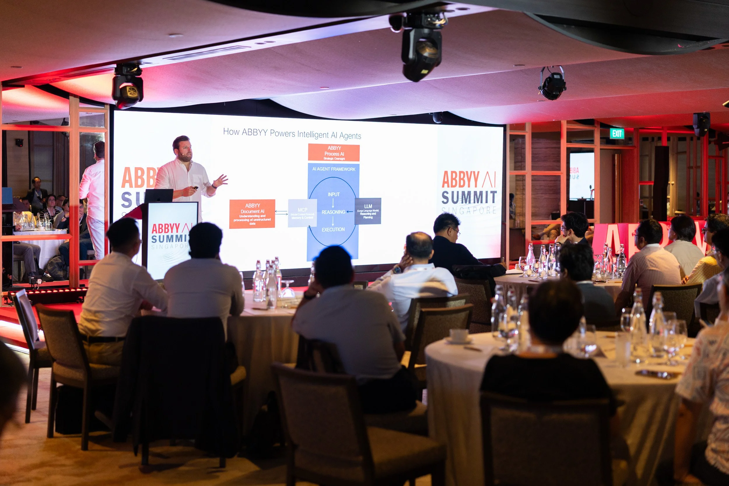  Medium shot of Maxime Vermeir speaking on stage during a product presentation session. 