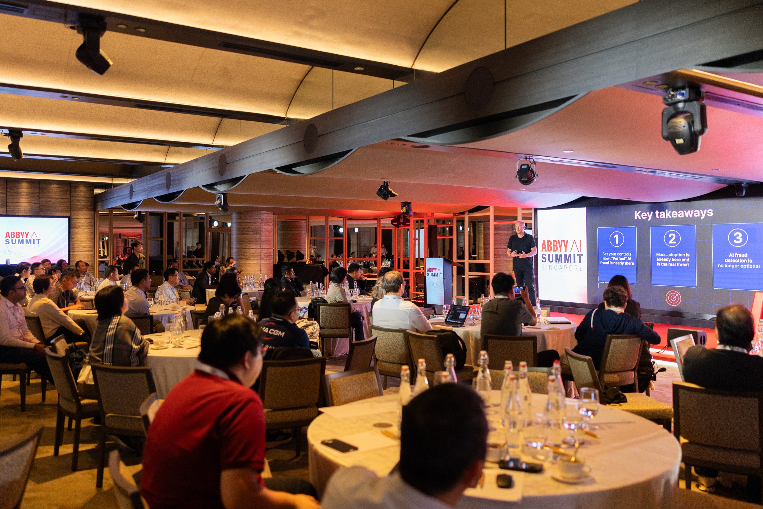  Wide angle stage photograph of Jan Syrinek addressing attendees in the PARKROYAL COLLECTION function room. 