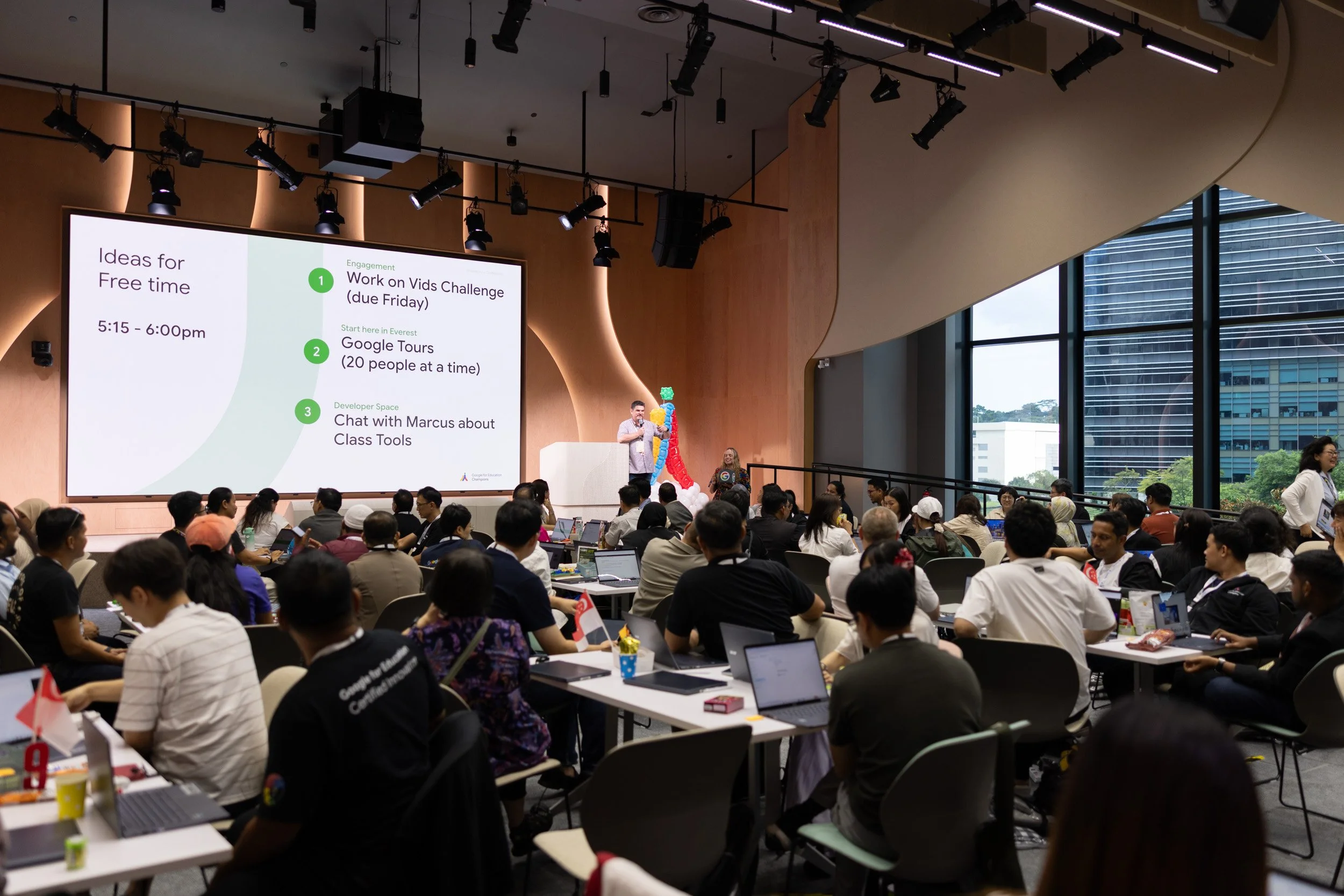  Wide angle stage photograph of Jim Sill closing the presentation in the symposium room. 