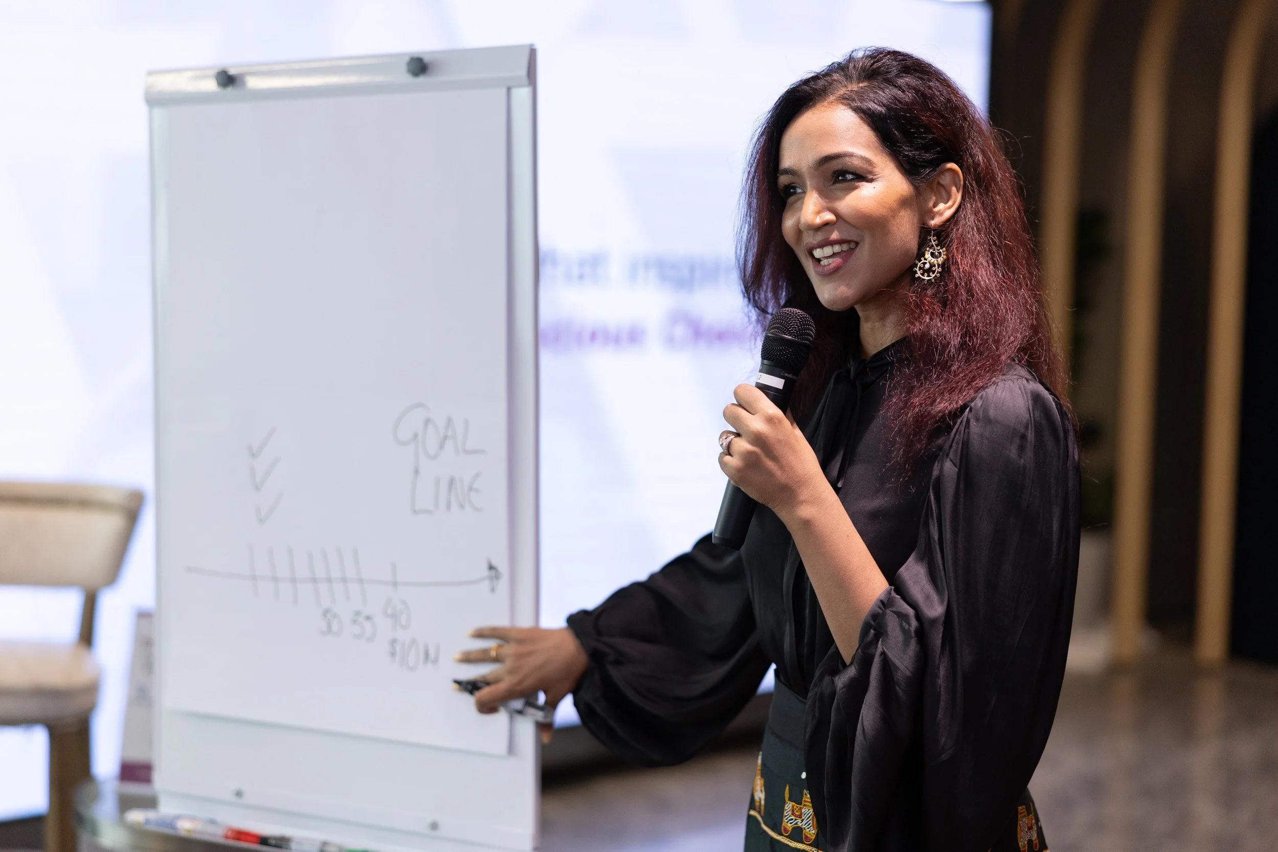  Close-up photo of Bhavna Toor pointing to presentation points mounted on a whiteboard display. 